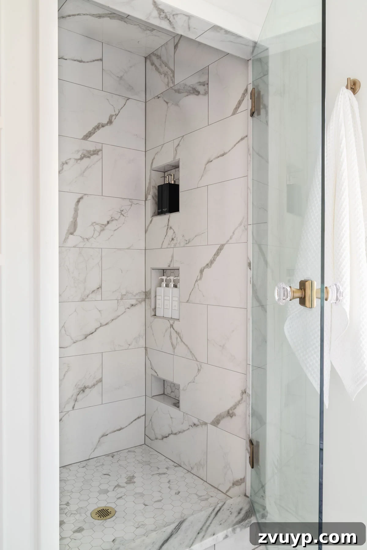 The Perfect Blend: Modern Vintage En Suite Bathroom Tour 17 Luxurious small shower featuring white marble-effect porcelain tile throughout, well-placed shower niches, and an elegant glass door with a custom knob