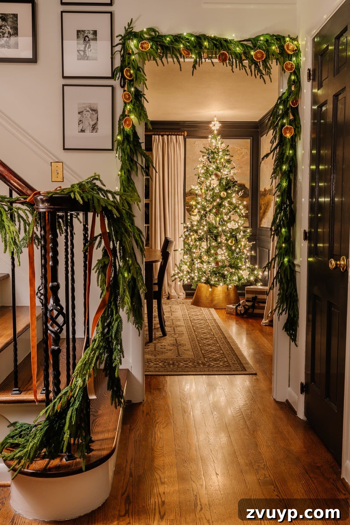 Enchanted Glow Tour 7 A festive Christmas candlelight doorway, adorned with holiday greenery and lights, leading from the stairs into a beautifully decorated dining room, capturing the inviting atmosphere of the season.