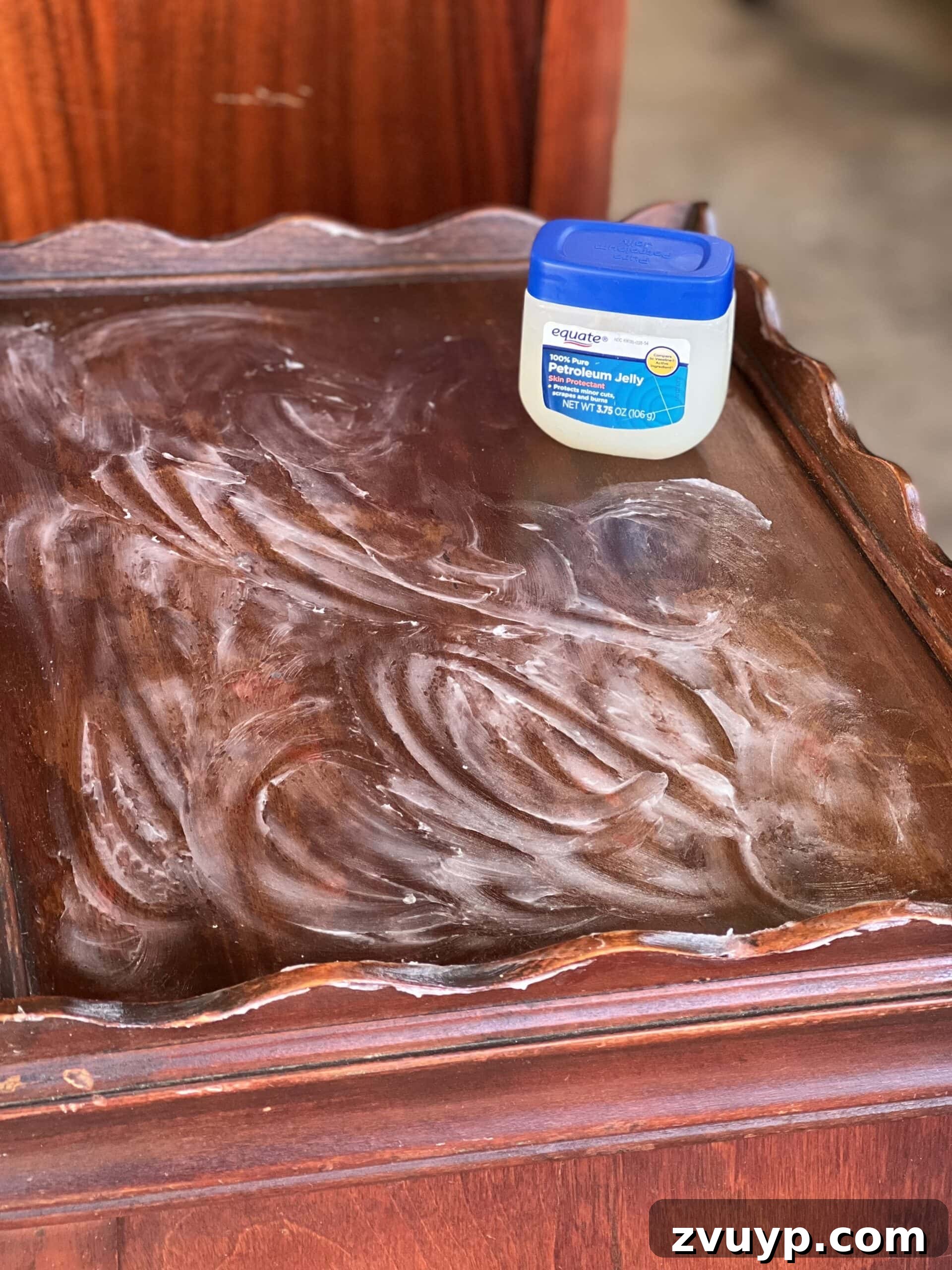 Wooden table with visible water damage being treated with Vaseline