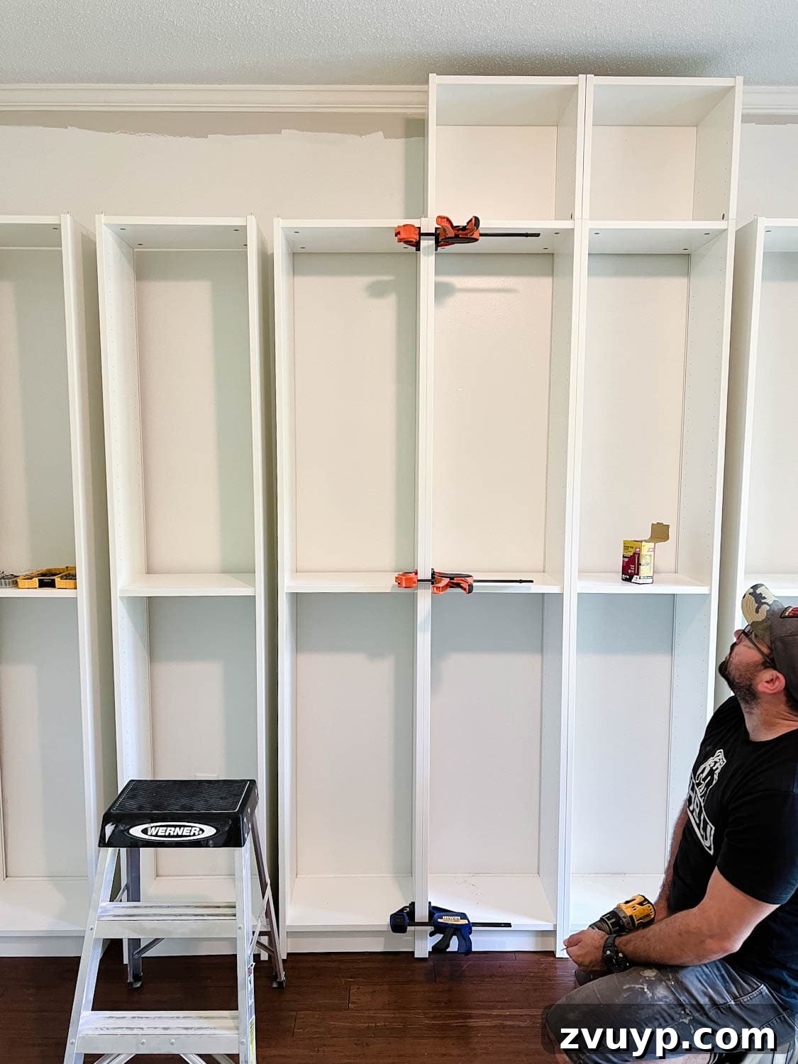 The IKEA Billy Hack: Custom Built-In Bookshelves Made Easy 11 using clamps to keep bookcases together to attach them with wood screws to make diy built in bookshelves