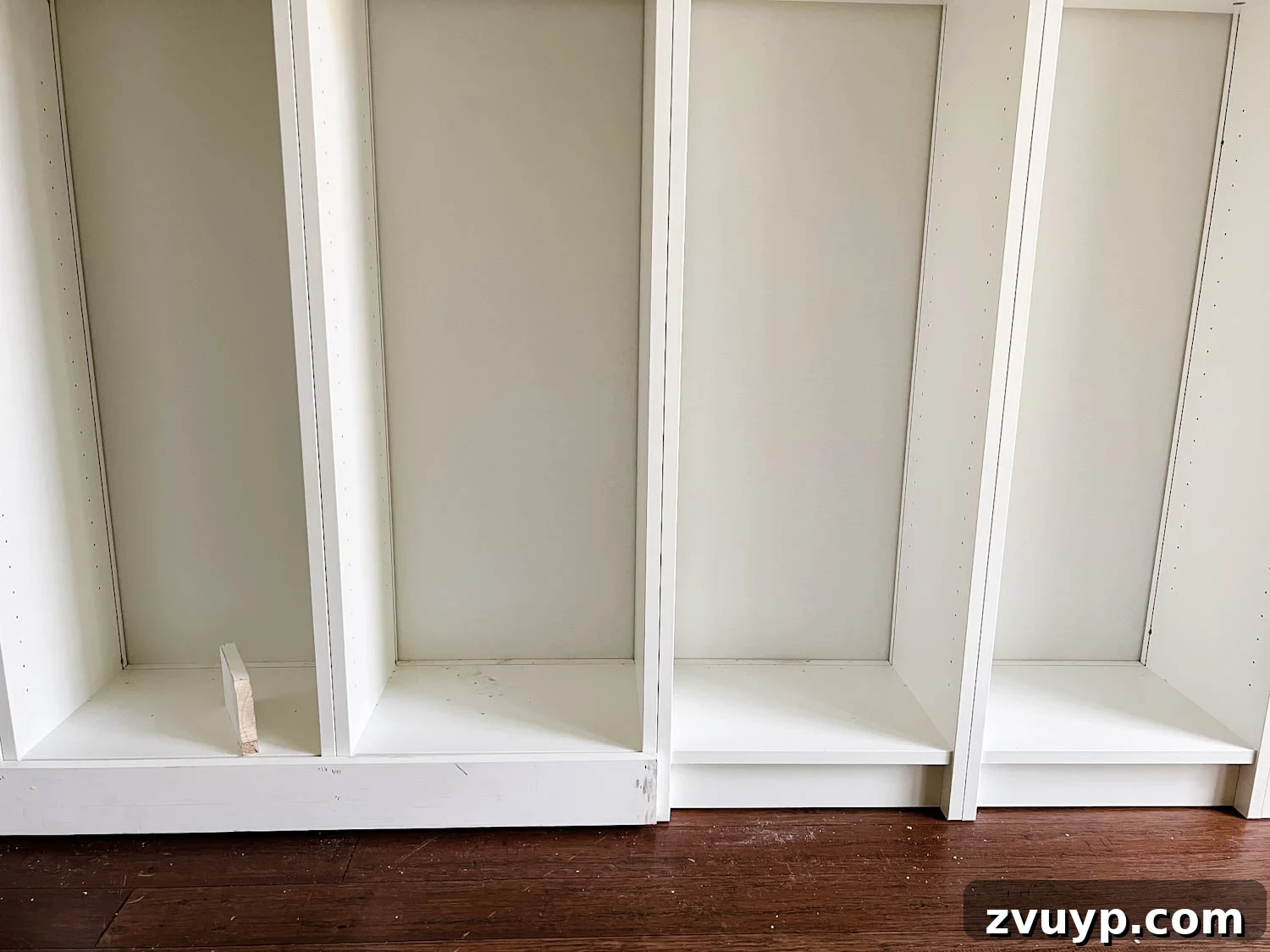 The IKEA Billy Hack: Custom Built-In Bookshelves Made Easy 15 adding 1x4 boards to the bottom of bookcases to make them look flush for DIY built in bookshelves
