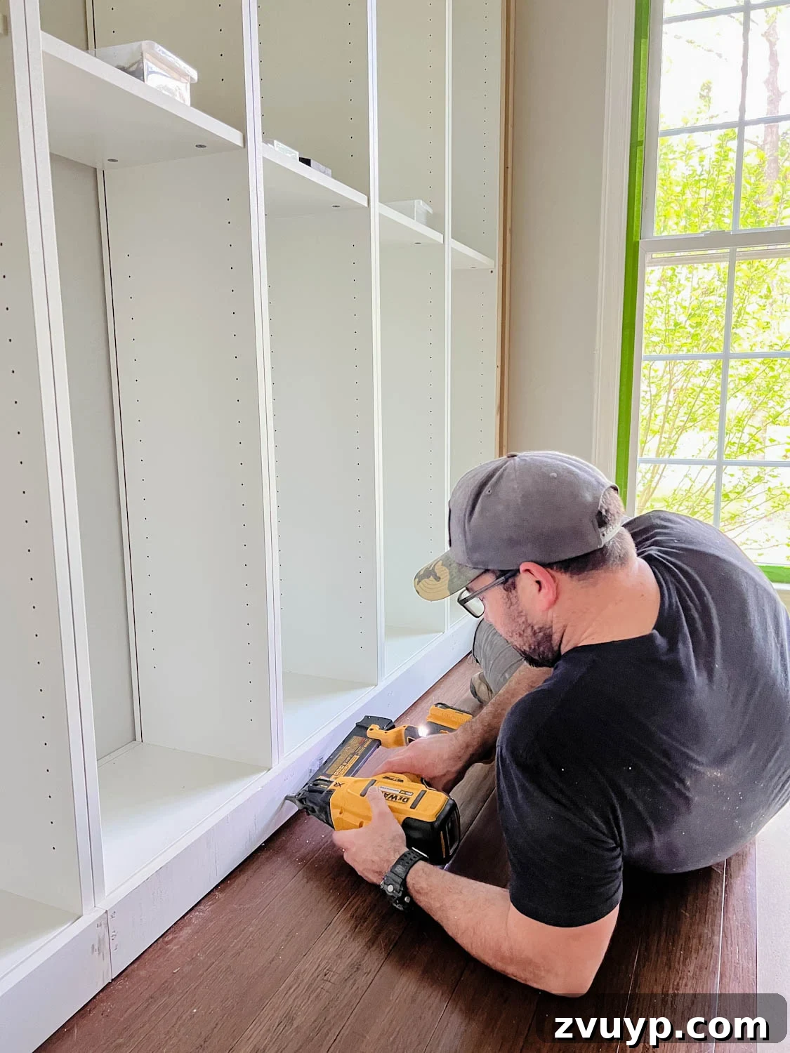 The IKEA Billy Hack: Custom Built-In Bookshelves Made Easy 18 attaching 1x4 board to the bottom of bookcases using a finish nailer for DIY built in bookshelves