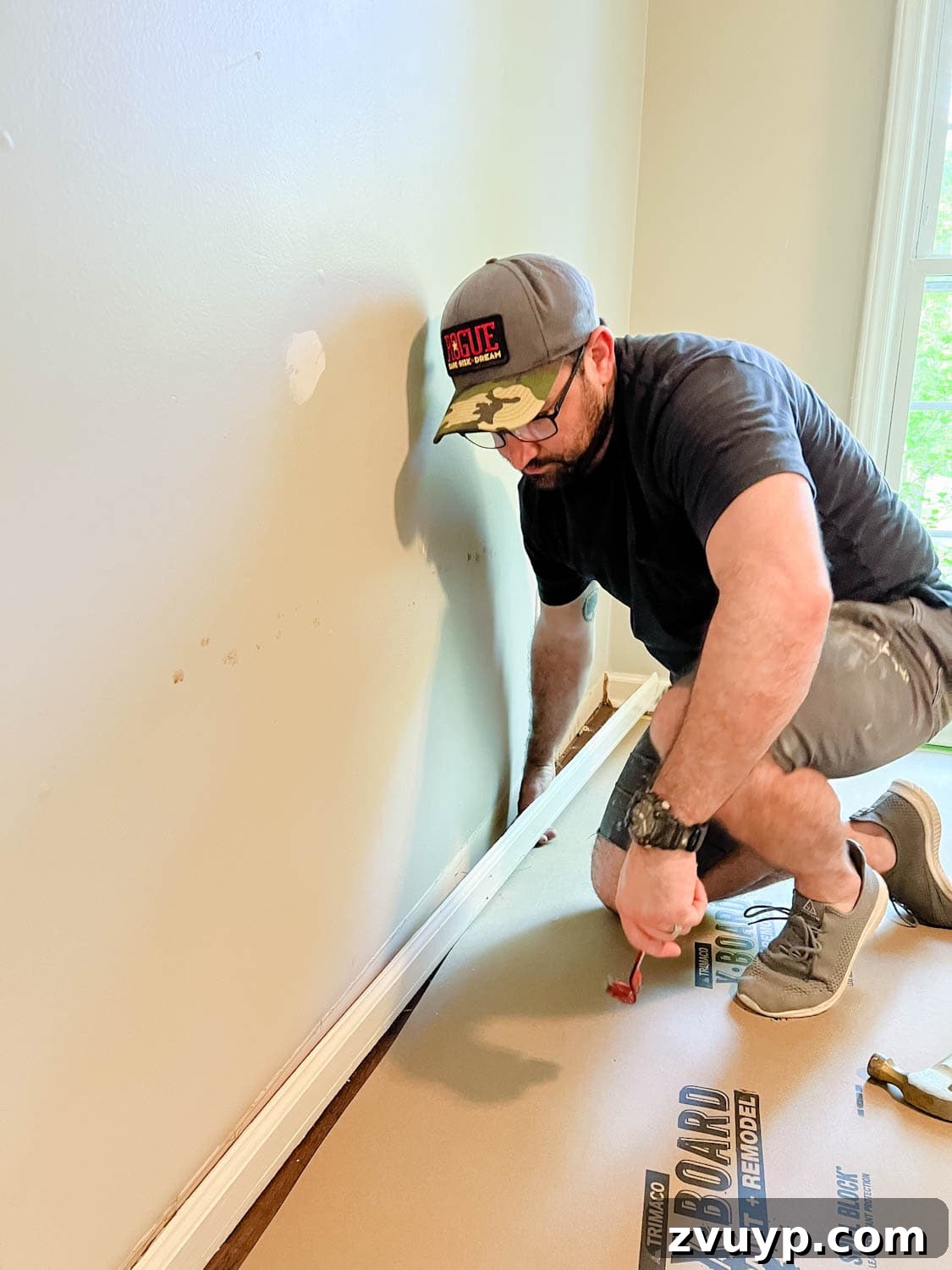 The IKEA Billy Hack: Custom Built-In Bookshelves Made Easy 4 removing a baseboard from a wall using a pry bar and hammer