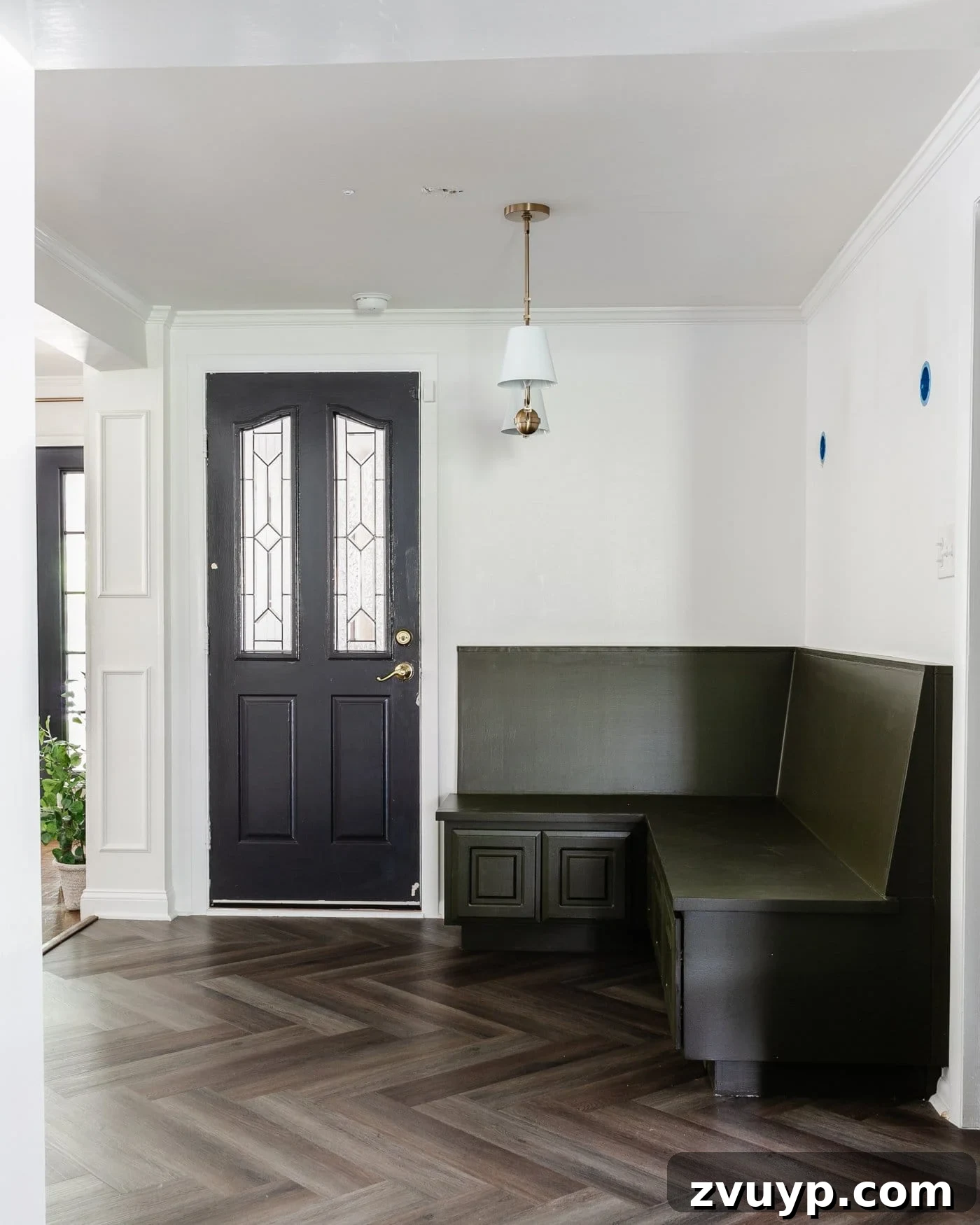 Corner Banquette Refresh and Hidden Vent Hacks 2 Inviting breakfast nook featuring an olive green corner banquette, a contrasting black door, crisp white walls, and stylish herringbone LVP floors.