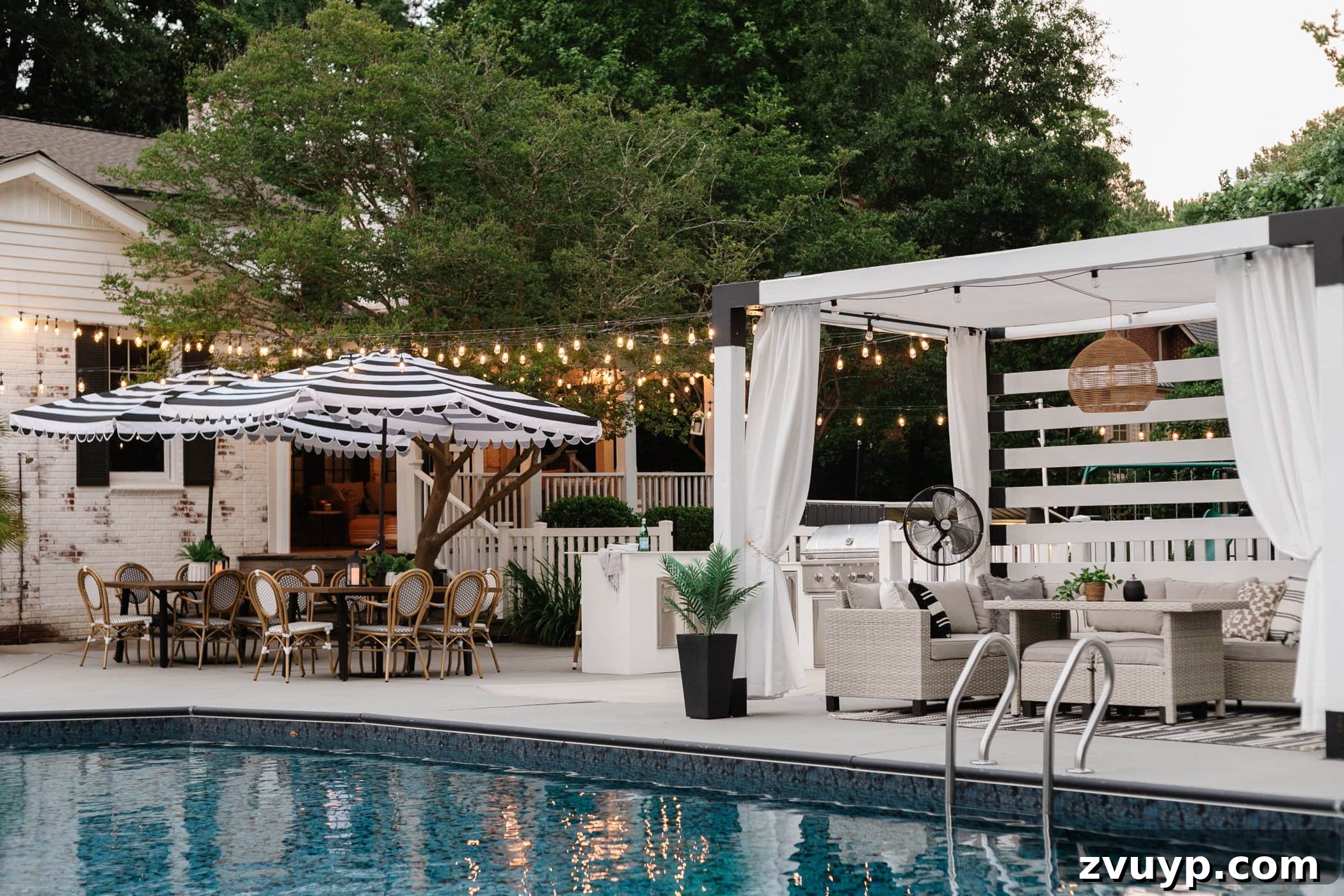 No Poles, No Problem: Creative Ways to Hang Backyard String Lights 48 string lights hanging around a pool with pergola and outdoor dining tables