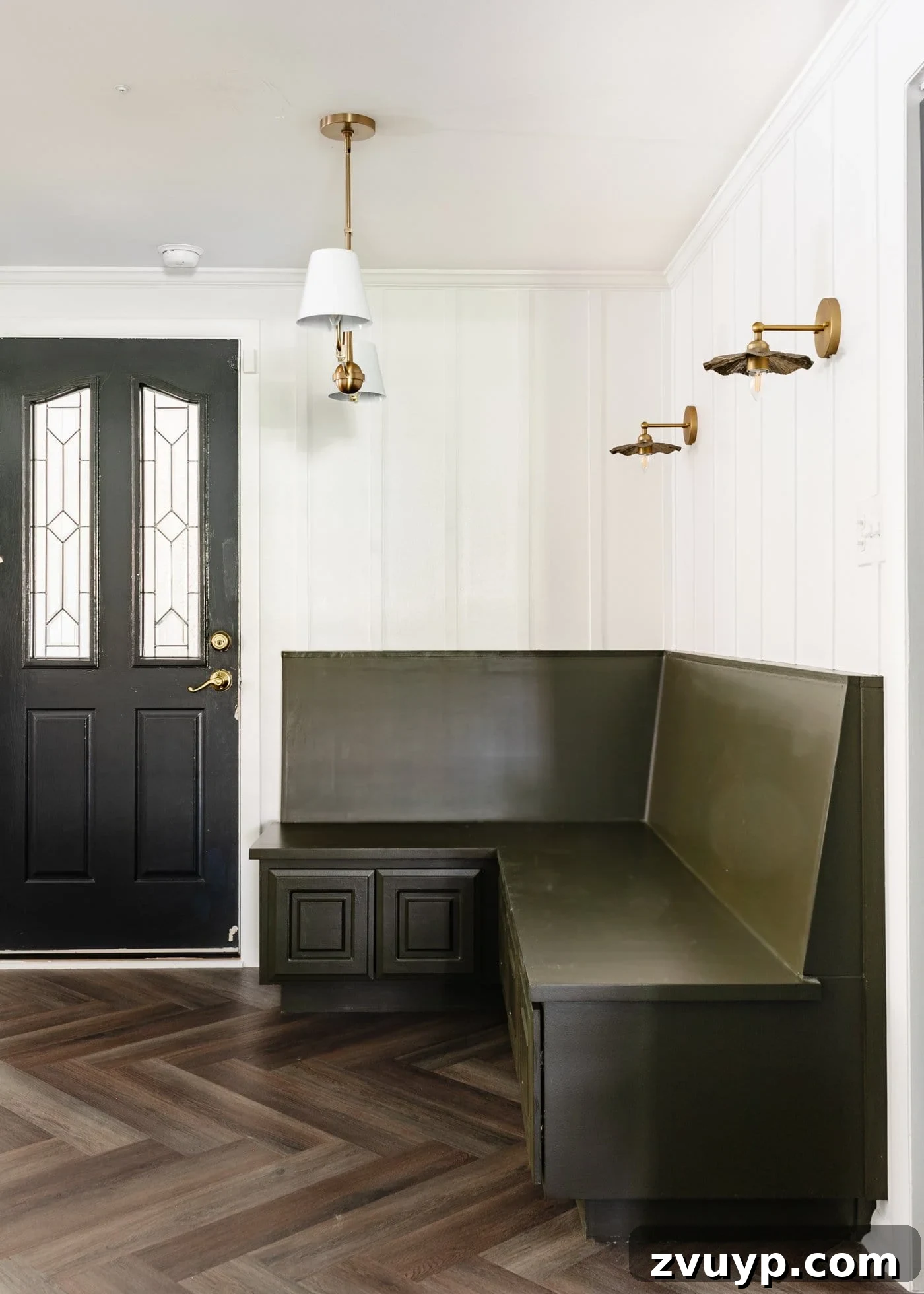 DIY Batten Wall Hack: Lattice Strips for an Affordable Look 13 An inviting breakfast nook featuring an olive green banquette bench, a crisp white batten wall, elegant herringbone floors, and a sophisticated black door, creating a harmonious and stylish space.