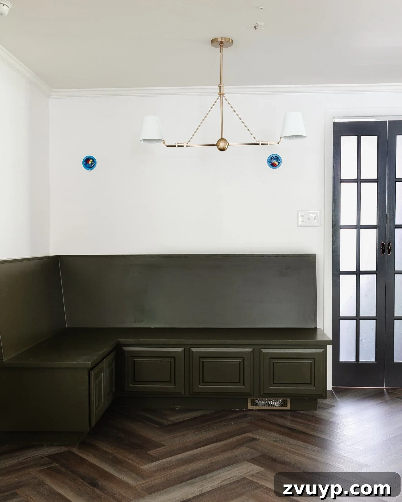 DIY Batten Wall Hack: Lattice Strips for an Affordable Look 3 A charming breakfast nook with an olive green banquette, elegant herringbone floors, pristine white walls featuring a DIY batten wall, and a stylish black bifold French door.