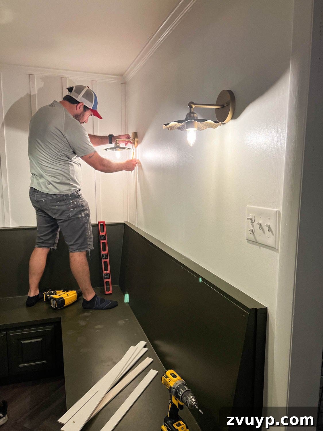 DIY Batten Wall Hack: Lattice Strips for an Affordable Look 7 A close-up shot of a person installing lattice strips onto a wall for DIY batten wall molding, carefully dry-fitting each piece before permanent attachment to ensure a perfect alignment.