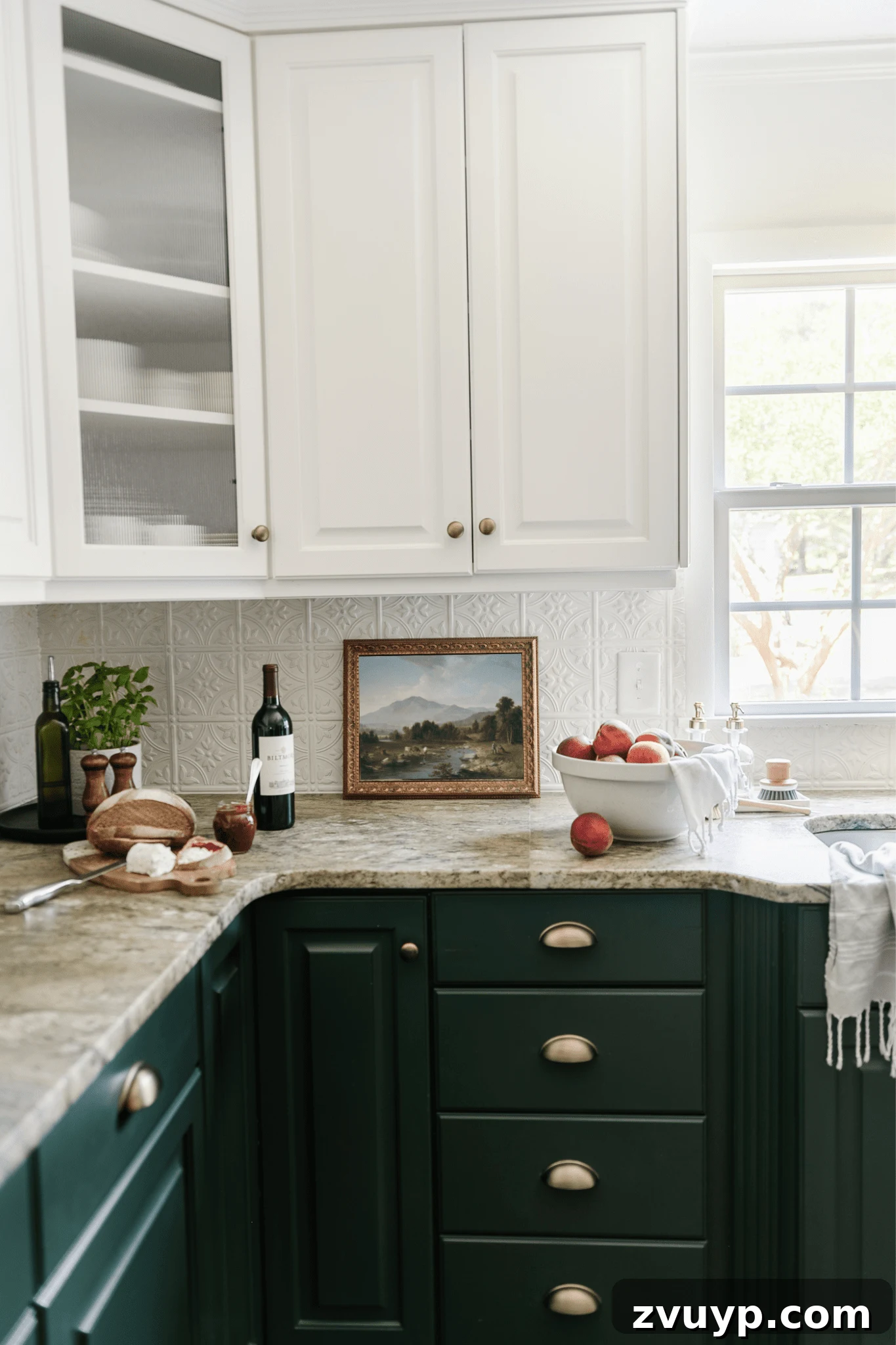 framed landscape oil painting print as kitchen art on a countertop with bowl of peaches and tray with a plant