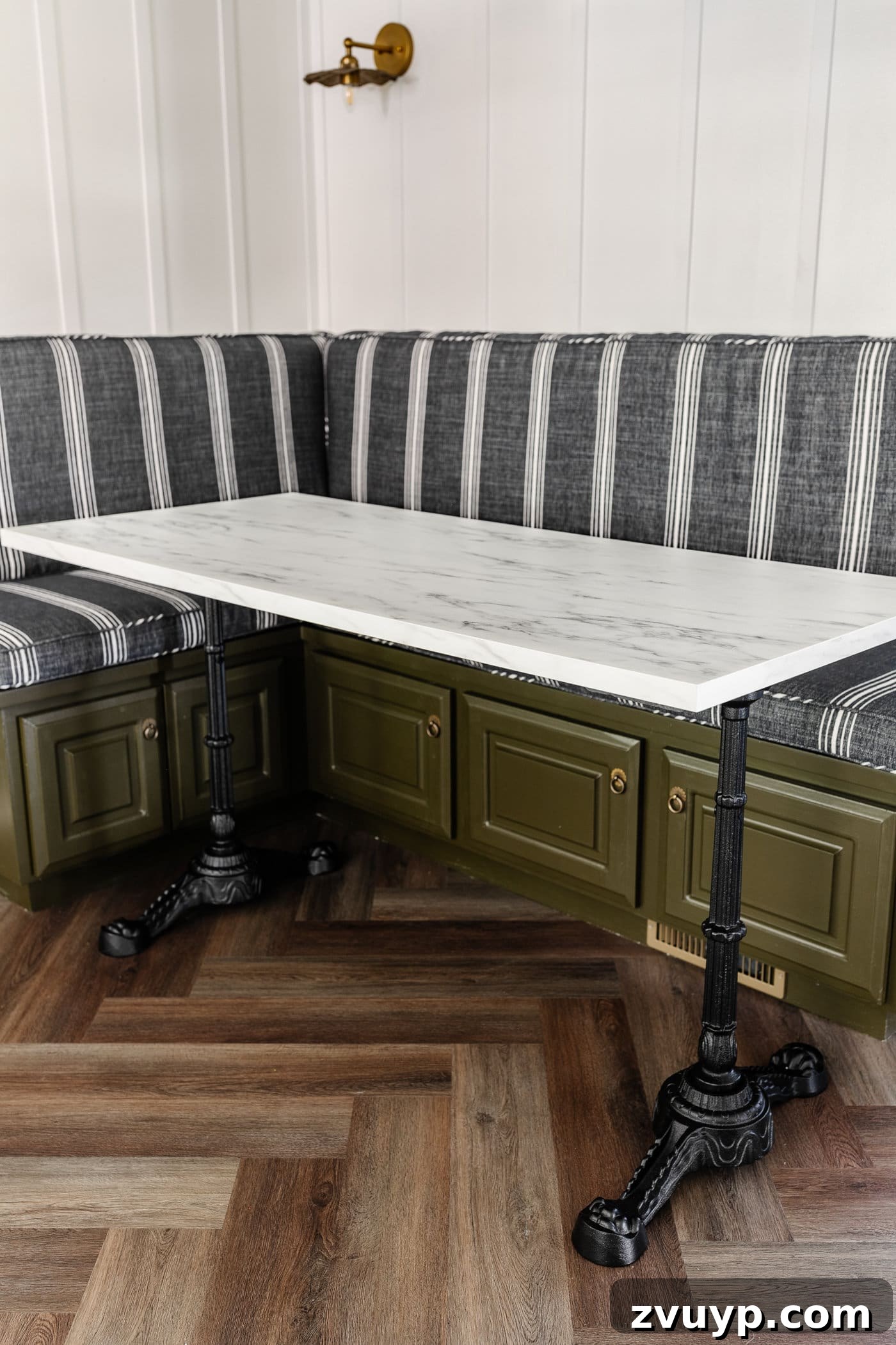 One Hour Faux Marble Dining Table Makeover 11 Parisian style faux marble dining table with cast iron pedestal legs against an olive green banquette with charcoal striped bench cushions and herringbone wood floors