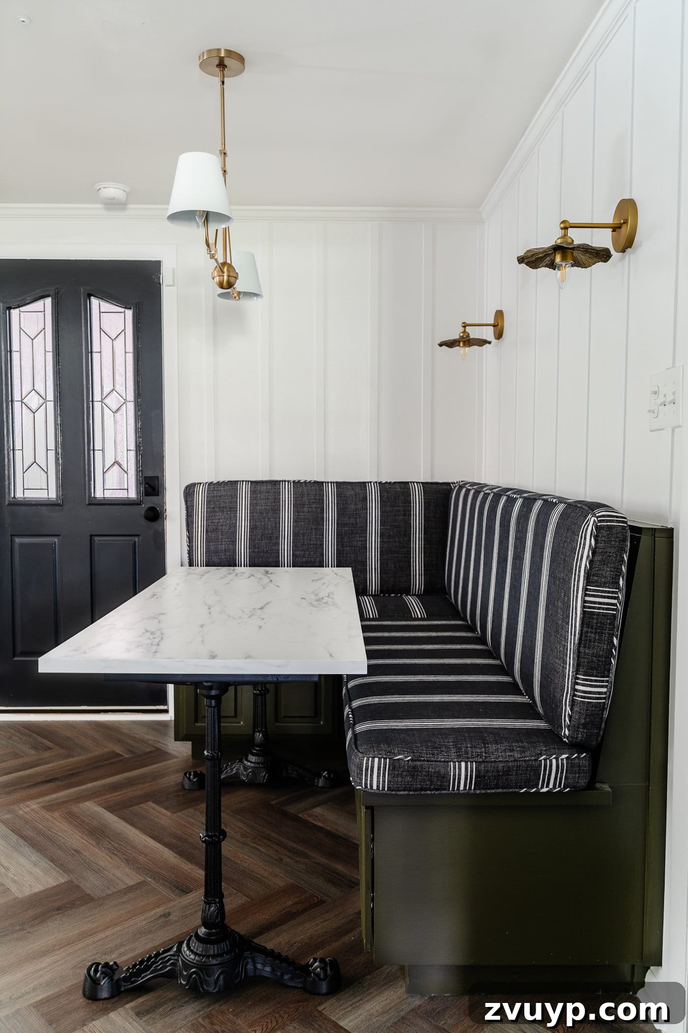 One Hour Faux Marble Dining Table Makeover 12 Parisian style faux marble dining table with cast iron pedestal legs against an olive green banquette with charcoal striped bench cushions and herringbone wood floors