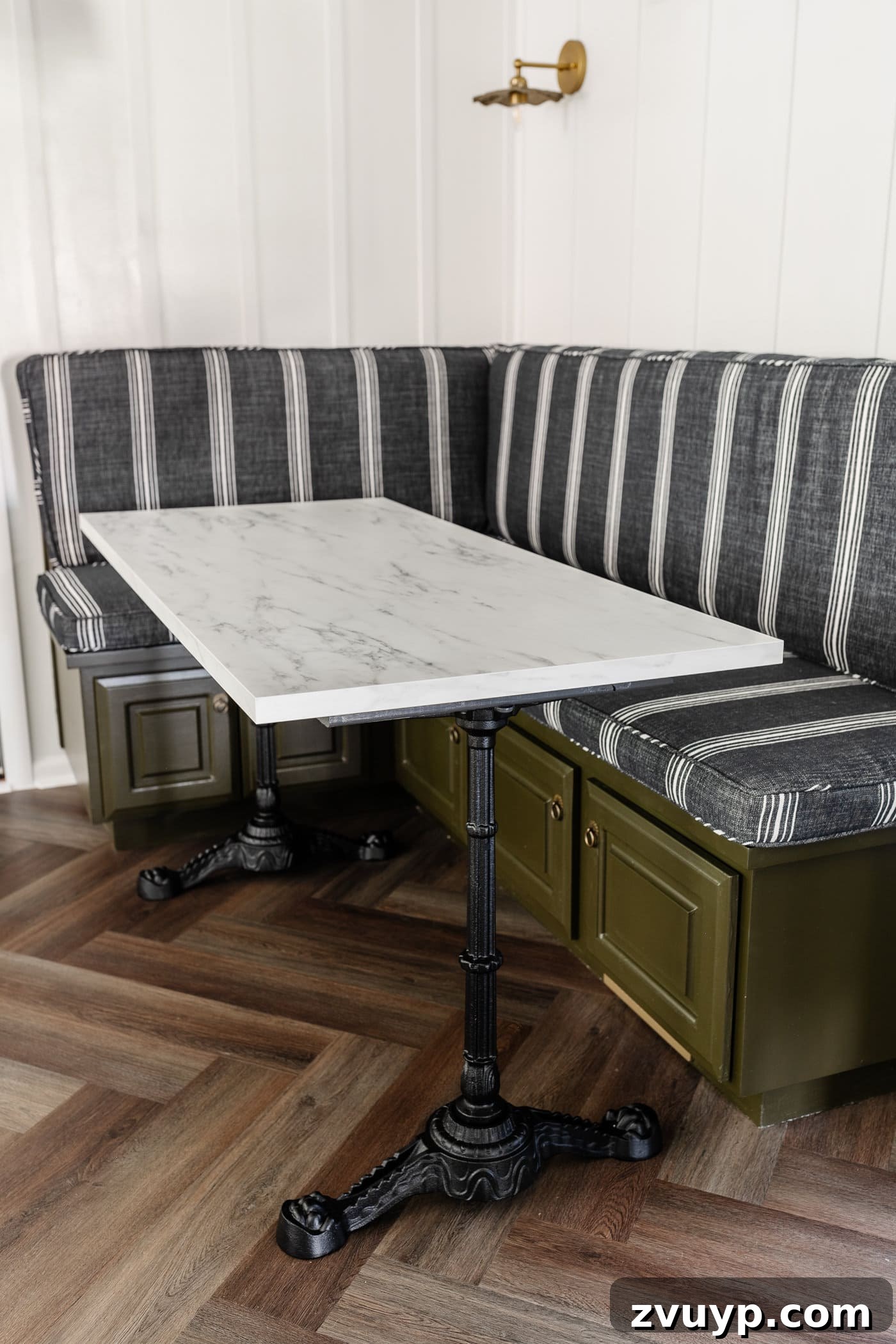 One Hour Faux Marble Dining Table Makeover 3 Parisian style faux marble dining table with cast iron pedestal legs against an olive green banquette with charcoal striped bench cushions and herringbone wood floors