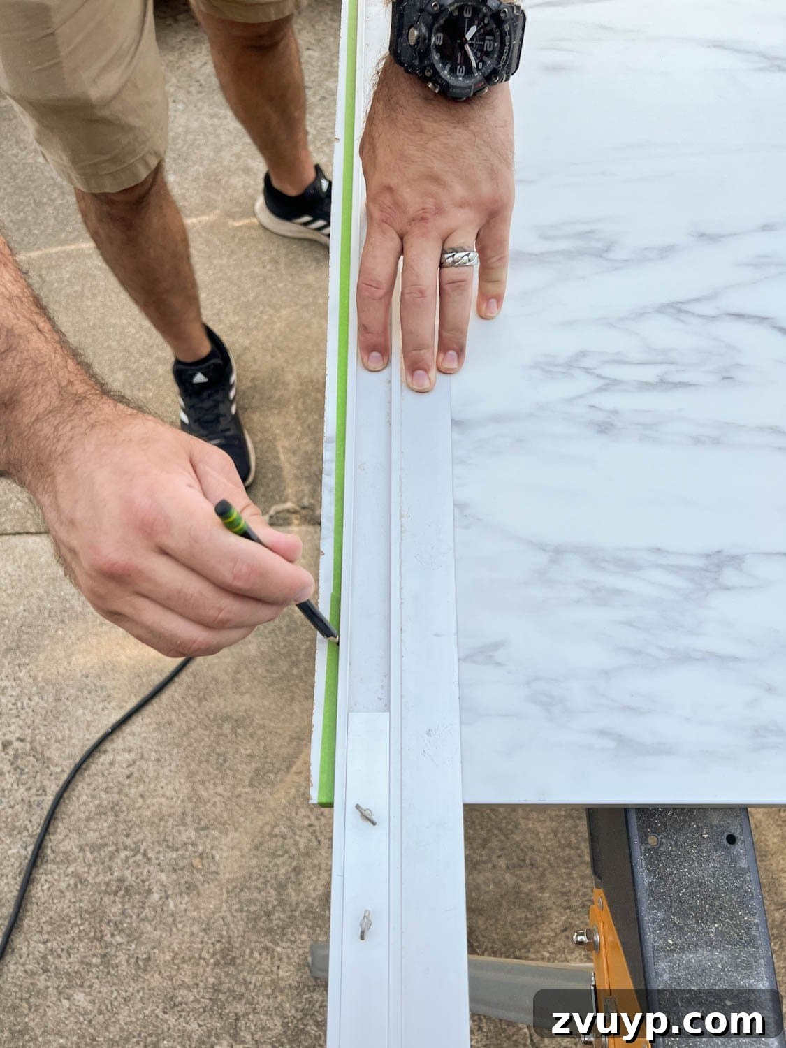 One Hour Faux Marble Dining Table Makeover 6 marking straight edge on masking tape on laminate faux marble countertop to be cut