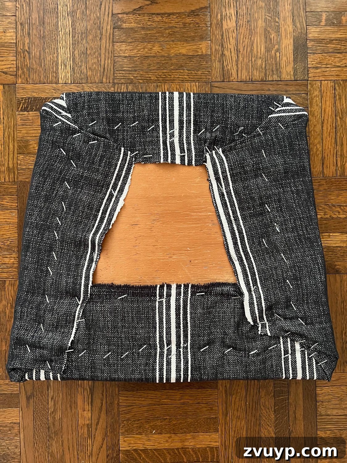 From Drab to Fab: DIY Dining Chair Reupholstery and Faux Bamboo Makeover 7 underside of recovering a dining chair seat with upholstery fabric and a staple gun