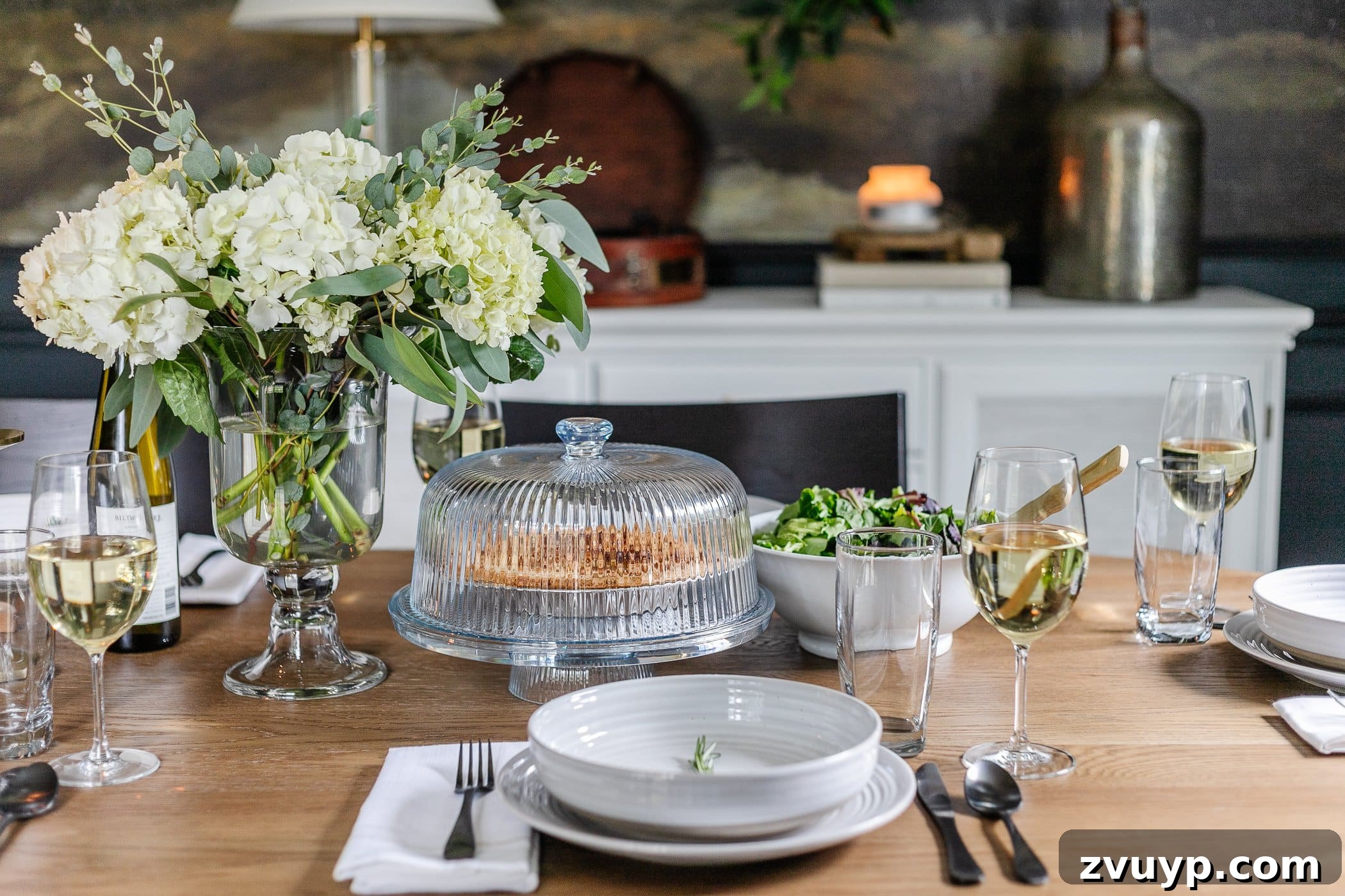 Your Go-To Guide for Flawless Table Settings, Every Time 8 a beautiful vase filled with fresh hydrangeas, alongside a simple place setting of gray dishes and a rosemary sprig, a cake dome, and a serving bowl of salad