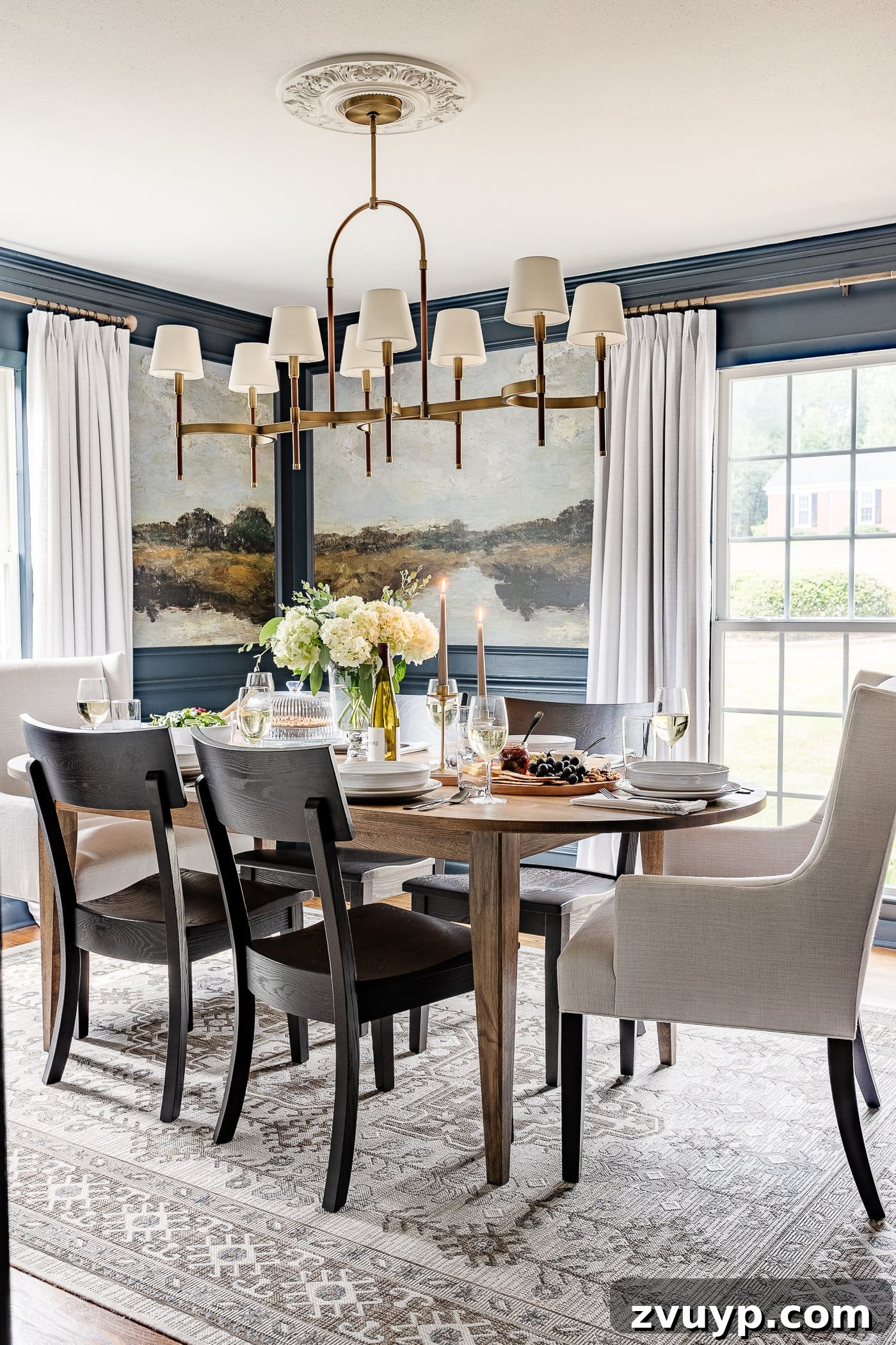 Our Home's Incredible 5-Year Transformation Tour 17 elegant navy blue dining room featuring stunning mural walls within picture frame molding, luxurious linen curtains, a sophisticated shaded chandelier, a classic wood oval dining table, comfortable linen head chairs, and stylish black dining chairs, creating a dramatic and inviting space