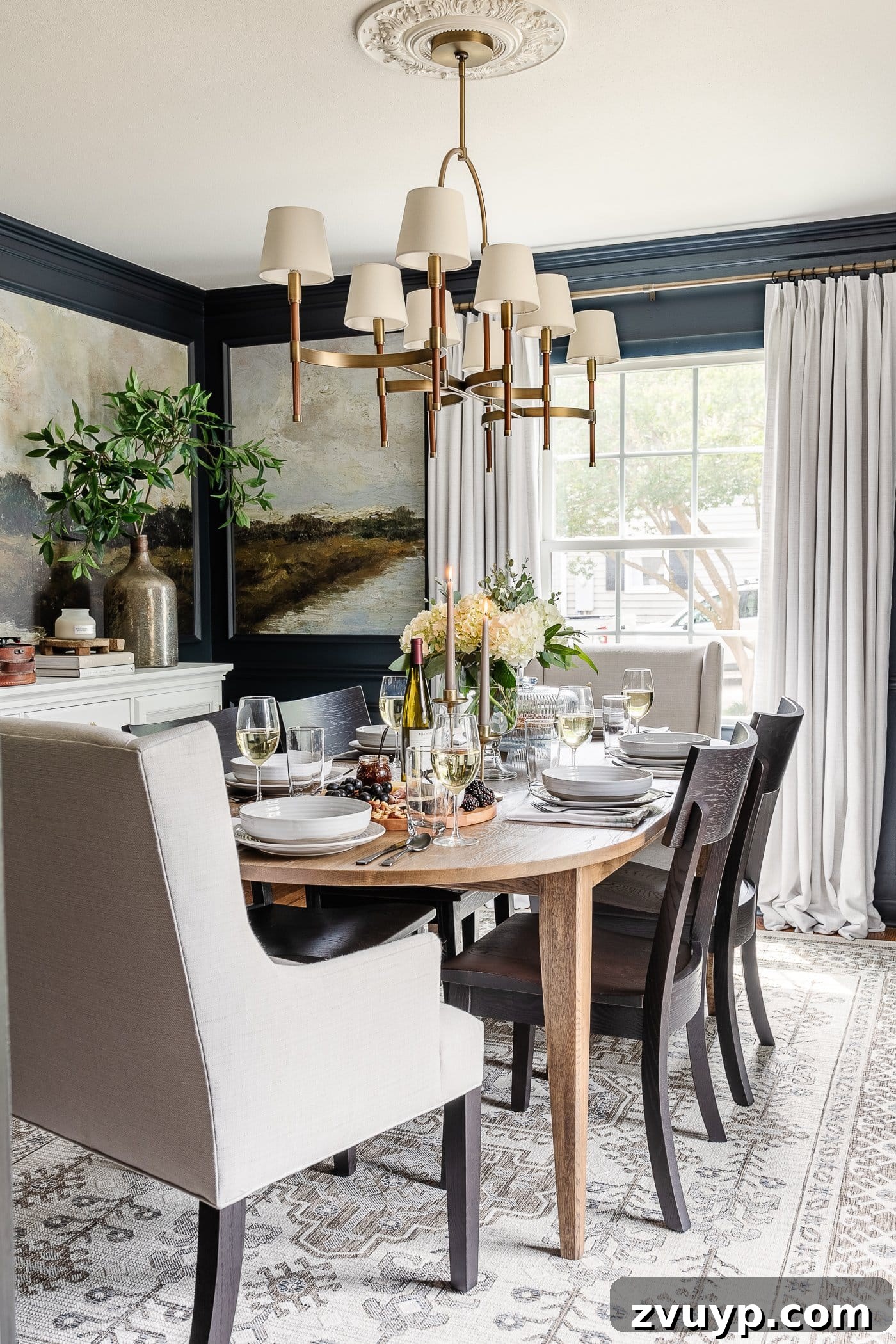 Our Home's Incredible 5-Year Transformation Tour 18 luxurious navy blue dining room with stunning mural walls set within elegant picture frame molding, soft linen curtains, a stylish shaded chandelier, a classic wood oval dining table, refined linen head chairs, and chic black dining chairs, creating an inviting and visually rich space