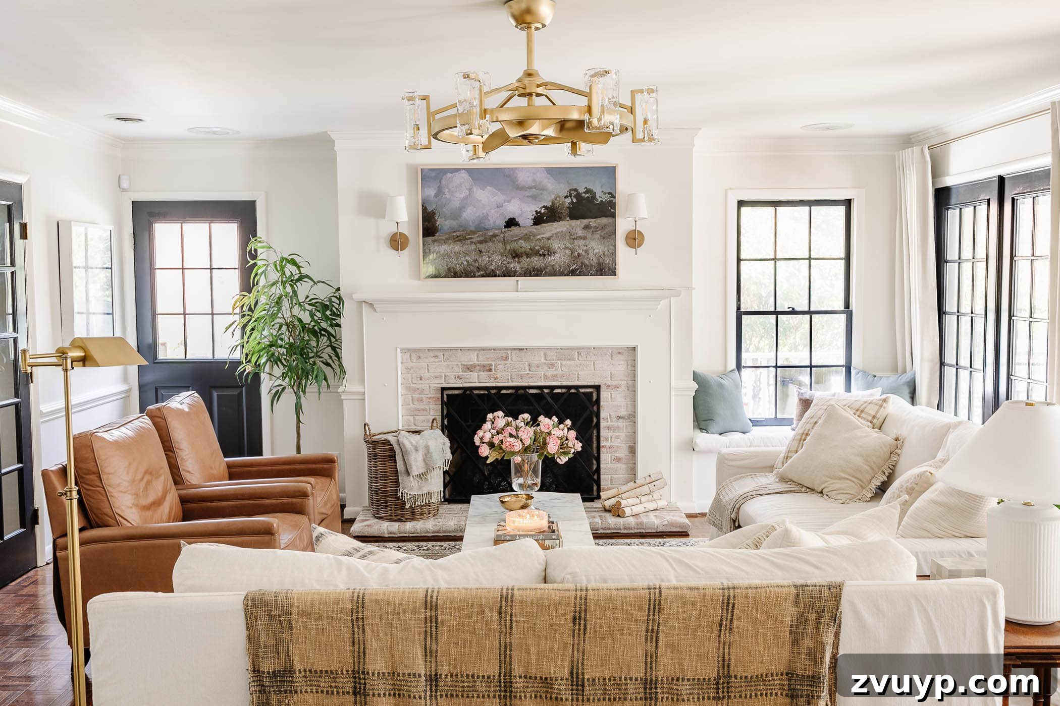 Our Home's Incredible 5-Year Transformation Tour 32 elegant white living room featuring a beautifully limewashed brick fireplace, a luxurious gold fandelier, comfortable white Pottery Barn sofas, stylish leather recliners, an innovative art TV, and sophisticated black French doors, creating a serene and inviting space