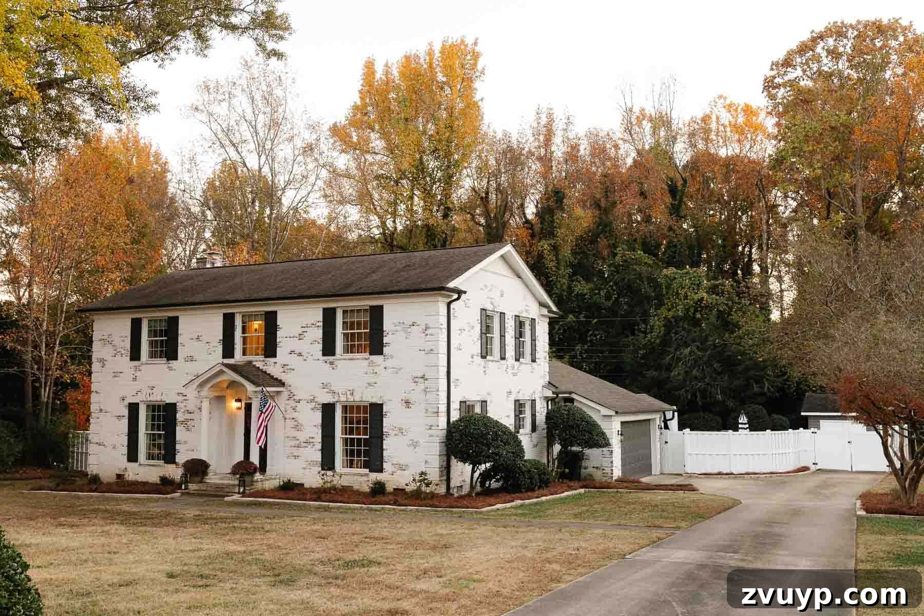 Our Home's Incredible 5-Year Transformation Tour 5 stunning white limewashed brick colonial house with contrasting black shutters, black doors, and a pristine white vinyl fence, showcasing a modern farmhouse aesthetic