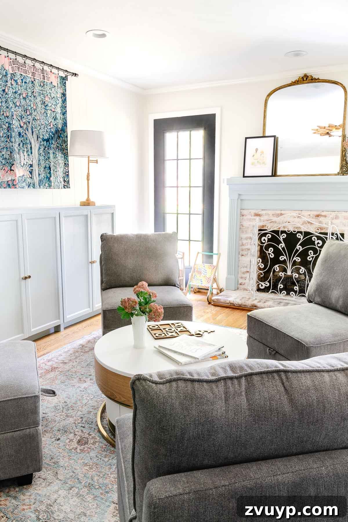 Our Home's Incredible 5-Year Transformation Tour 38 bright white playroom featuring a charming light blue mantel, efficient toy storage cabinets, a captivating William Morris tapestry, and versatile storage furniture, creating an organized and inviting space for children