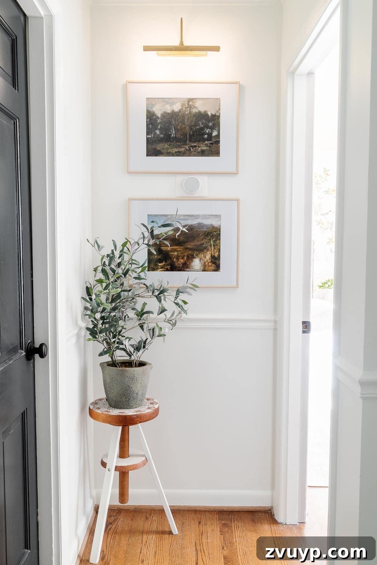 Our Home's Incredible 5-Year Transformation Tour 48 modern white hallway featuring sleek black doors and sophisticated landscape art, creating a clean and artistic aesthetic