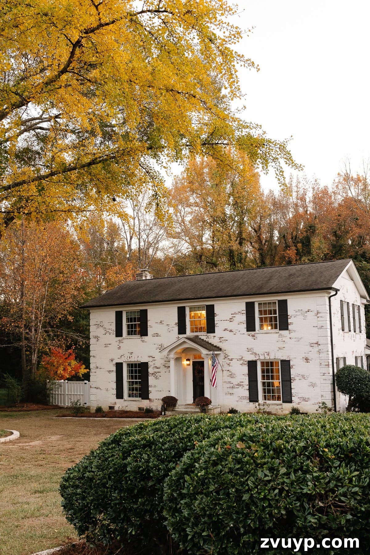 Our Home's Incredible 5-Year Transformation Tour 6 white limewashed brick colonial house with black shutters, black doors, and a pristine white vinyl fence, exuding modern curb appeal