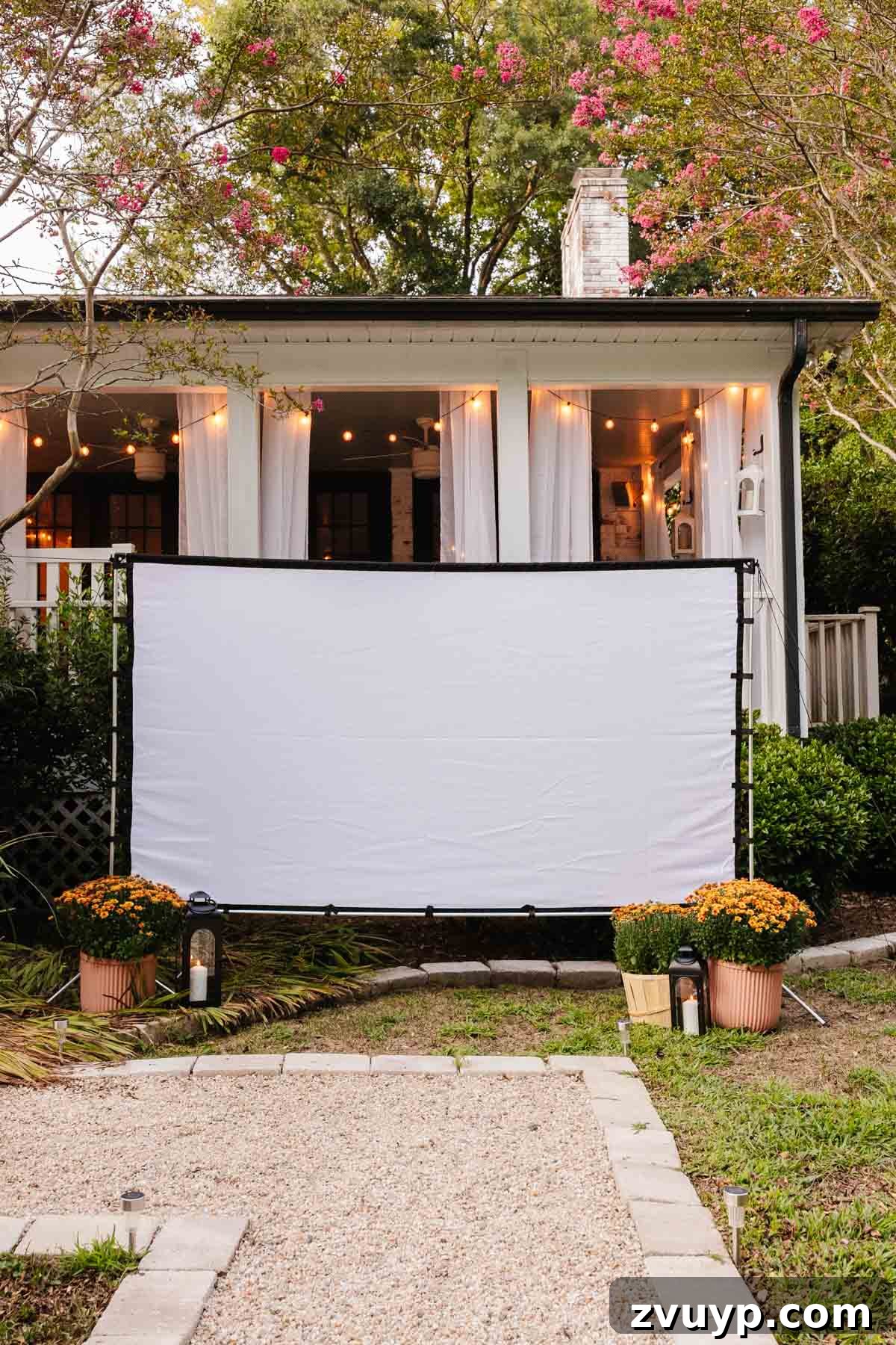 Top 100 Outdoor Films for an Unforgettable Backyard Cinema Experience 8 an outdoor theater movie screen set up in a backyard with lanterns and mums