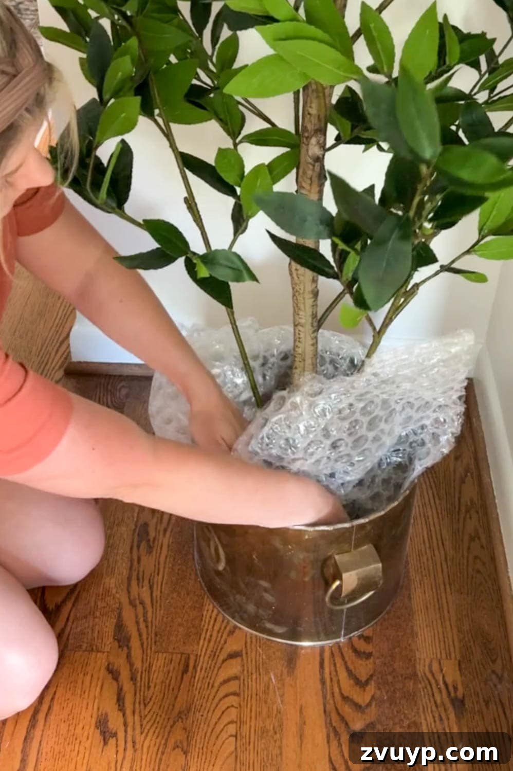 stuffing a thrifted brass planter at the base of an artificial tree