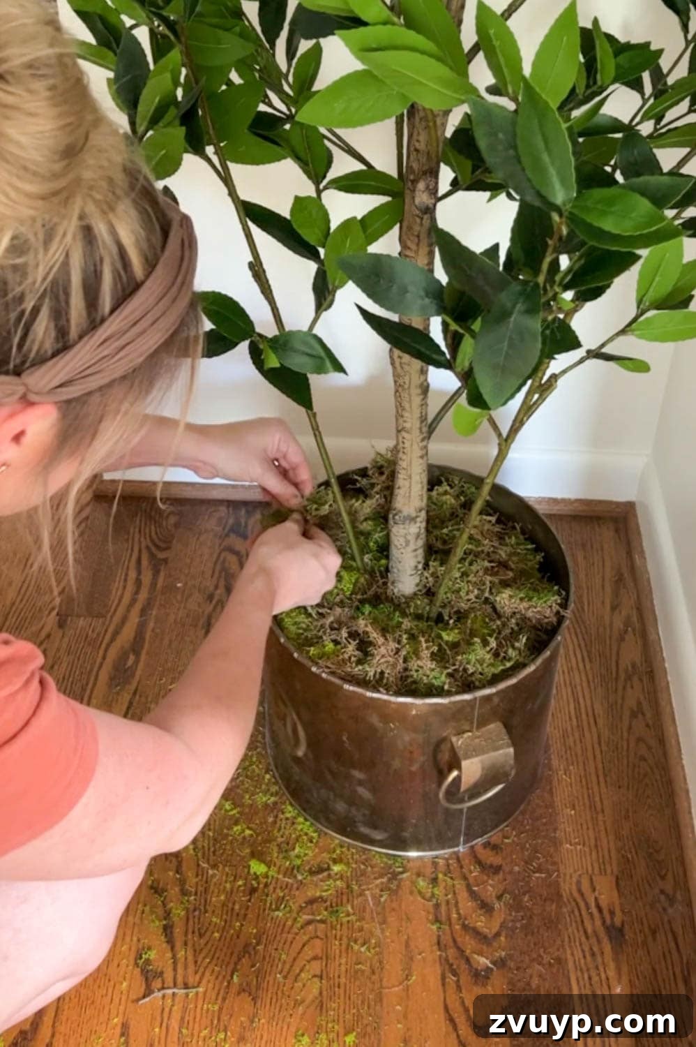 adding moss to a planter at the base of a faux tree