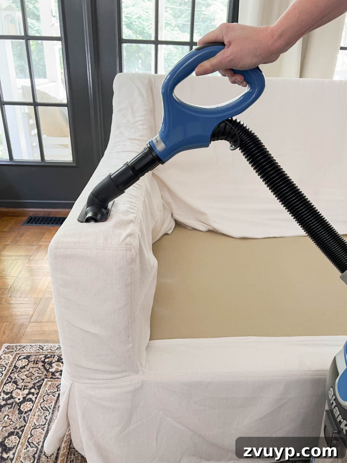 Revive Your Fabric Furniture The Ultimate Upholstery Deep Clean 10 Vacuuming a sofa slipcover with a wand attachment to remove baking soda, hair, dirt, and lint.