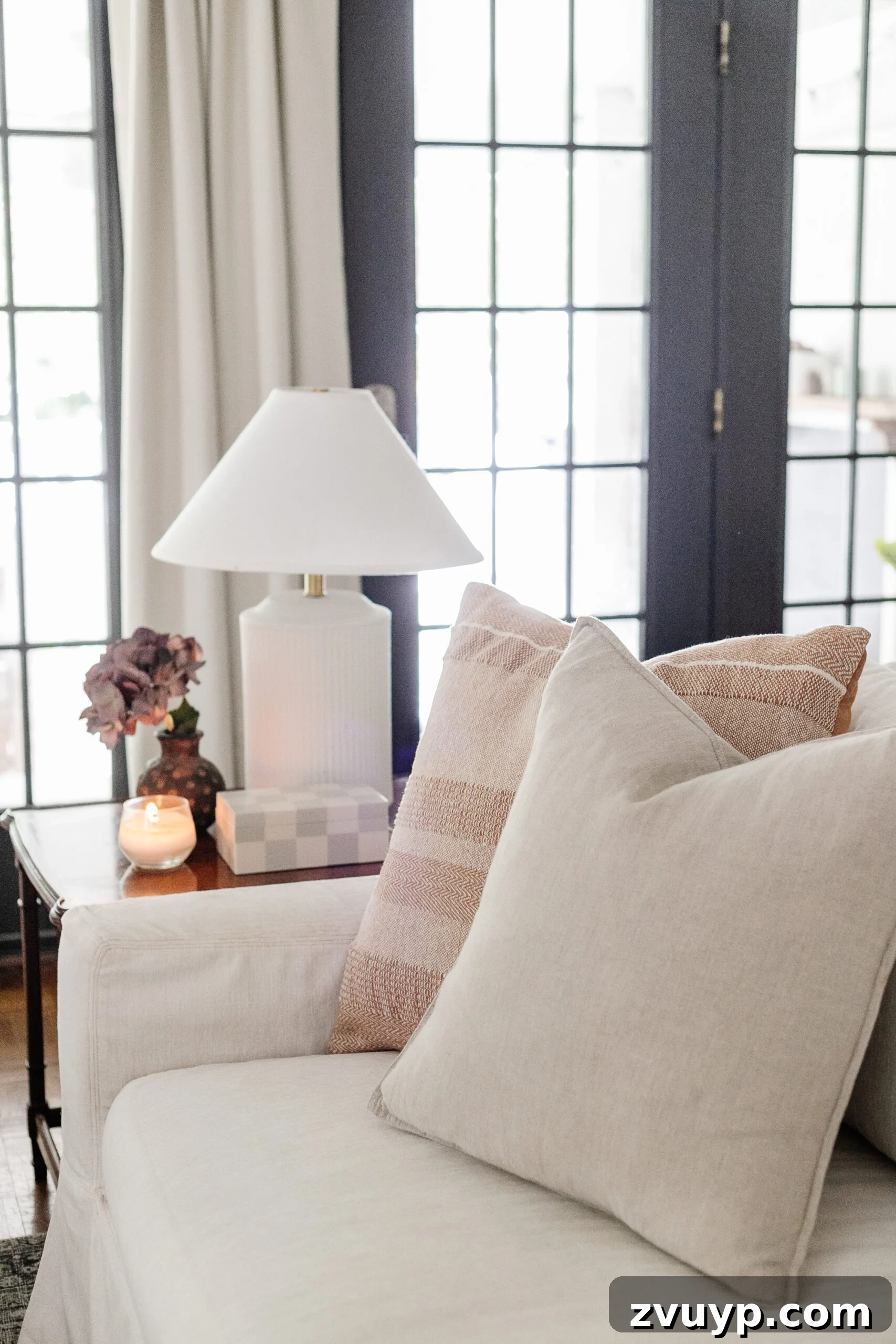 neutral throw pillows on a white couch with subtle end table decor and lamp