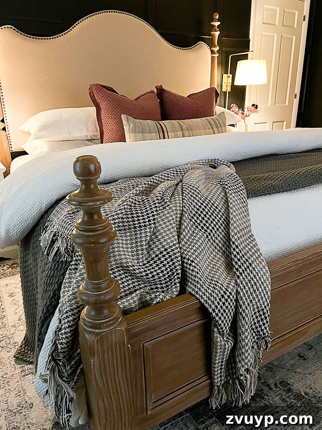 Sweet Dreams on a Budget: 10 Cozy Bedroom Tips for Ultimate Rest 8 An inviting bedroom scene featuring a stylish wood and upholstered bed, accented with soft mauve pillows and a chic houndstooth blanket, epitomizing cozy elegance.