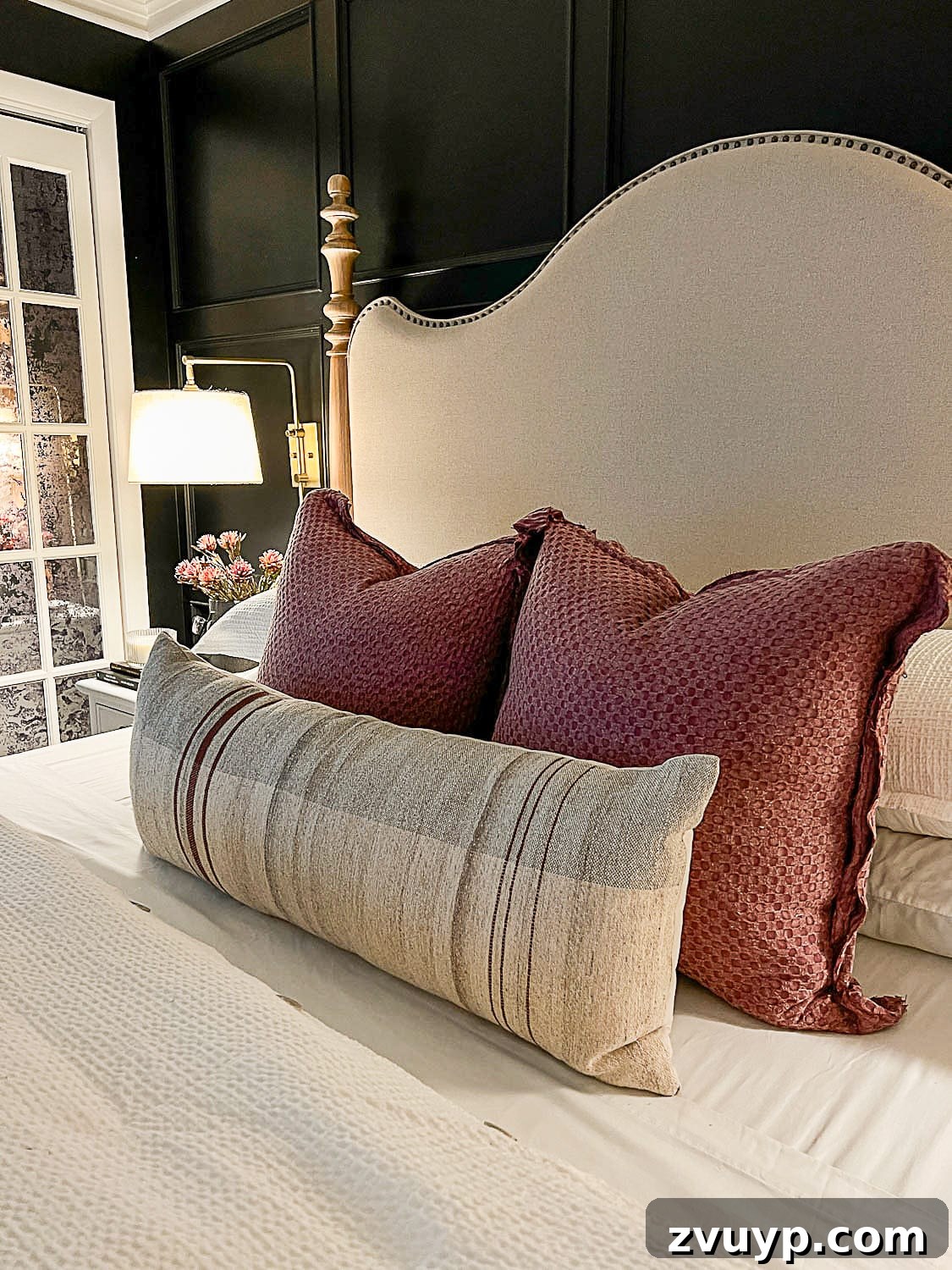 Sweet Dreams on a Budget: 10 Cozy Bedroom Tips for Ultimate Rest 9 Beautiful fall pillows arranged on a bed, softly illuminated by warm lamp light, creating a welcoming and cozy bedroom atmosphere.