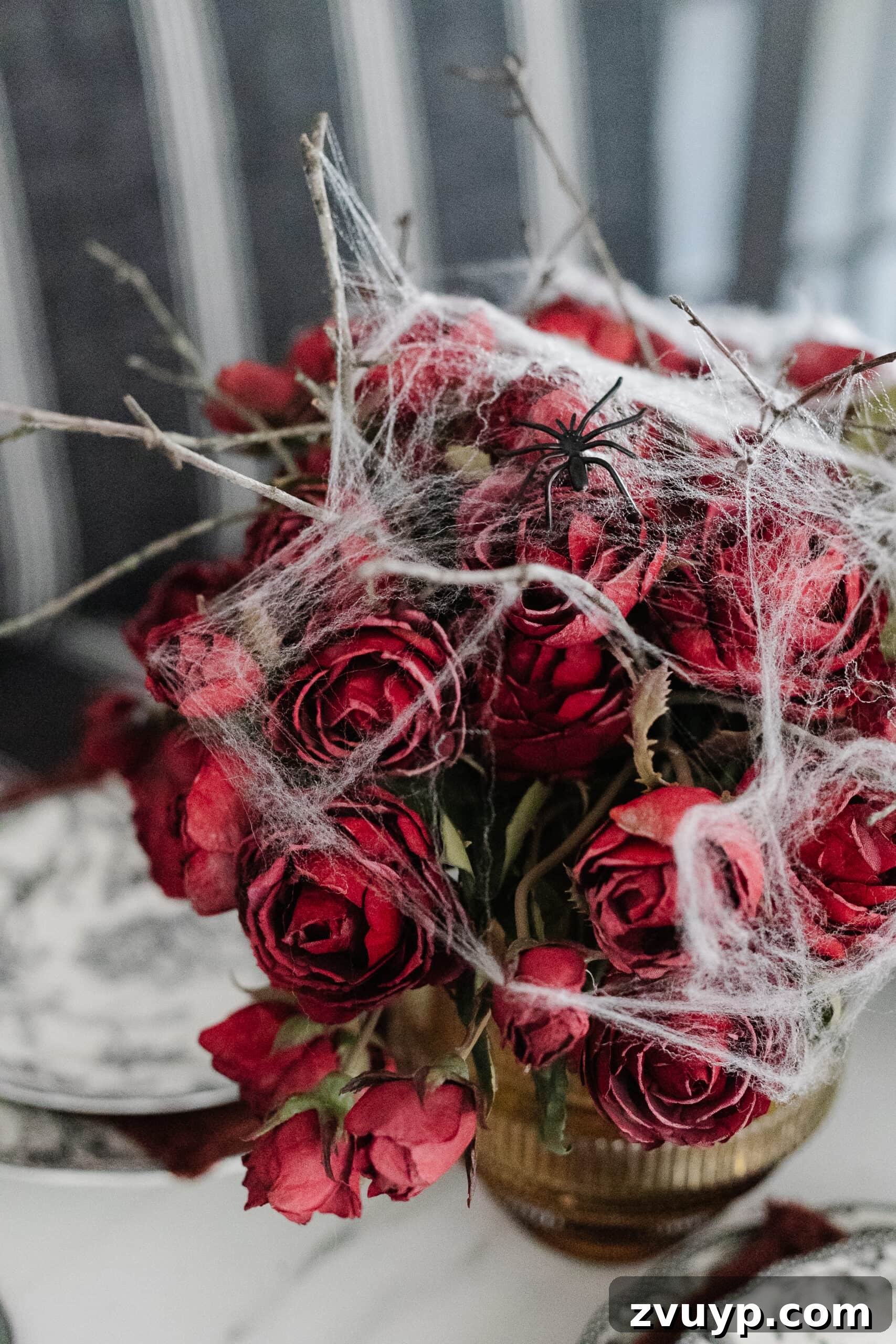 Killer Tablescapes for Your Halloween Murder Mystery 7 vase of red roses with spider webs for a simple Halloween flower arrangement