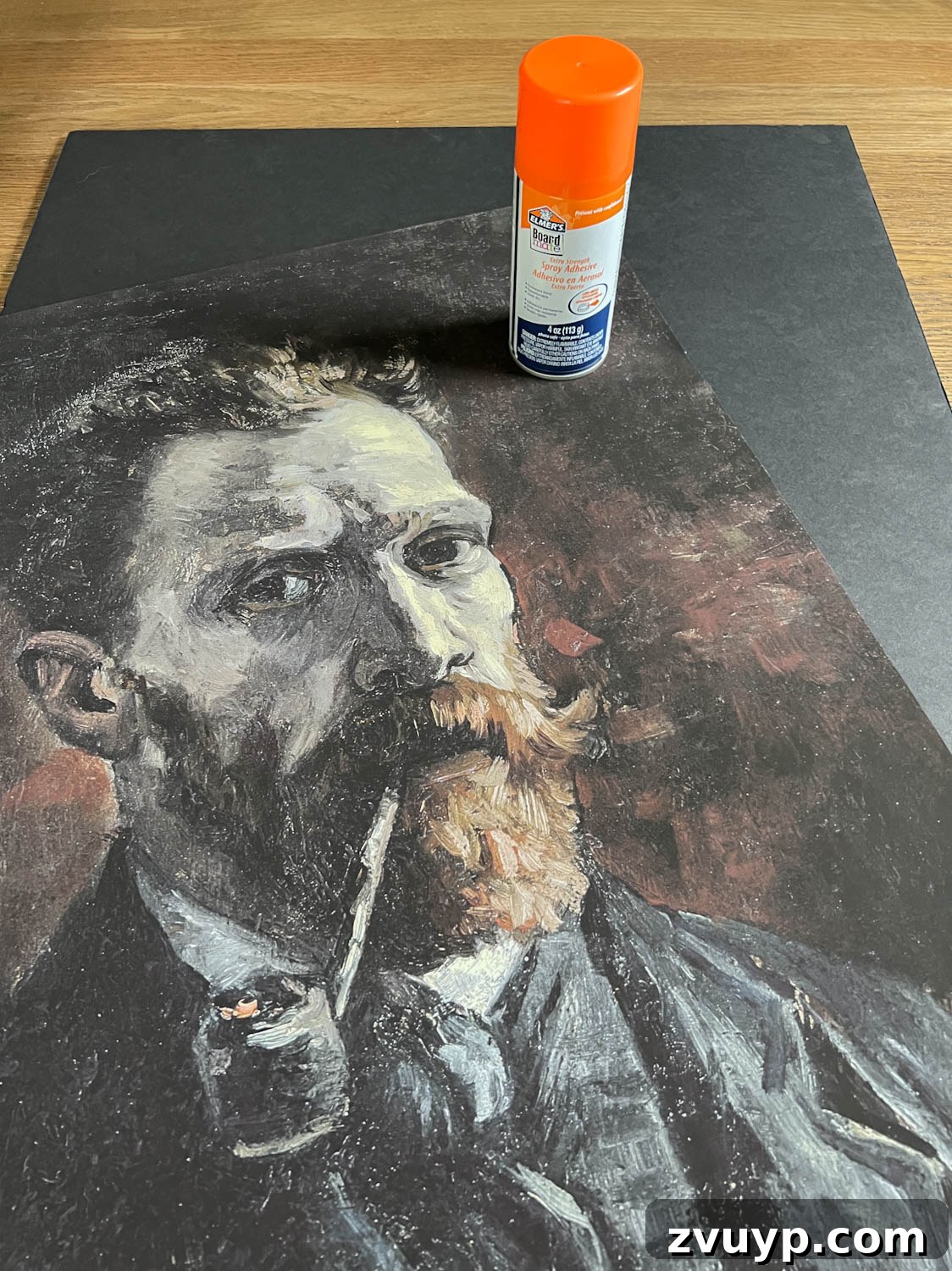 Making creepy art by using spray adhesive on foam board, ensuring a smooth bond for the art print.