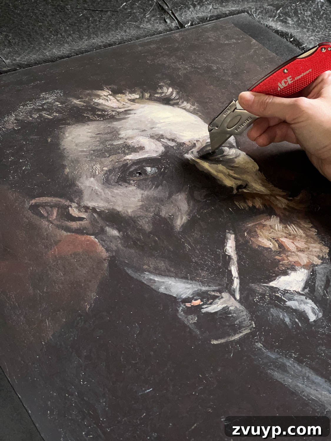 Cutting eyes out of art print with a utility knife to create glowing effect for Halloween decor.