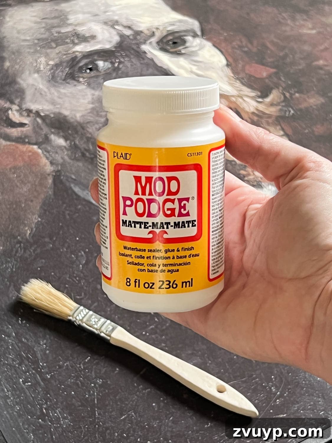 Matte Mod Podge being brushed onto the art print to create a vintage, textured look.