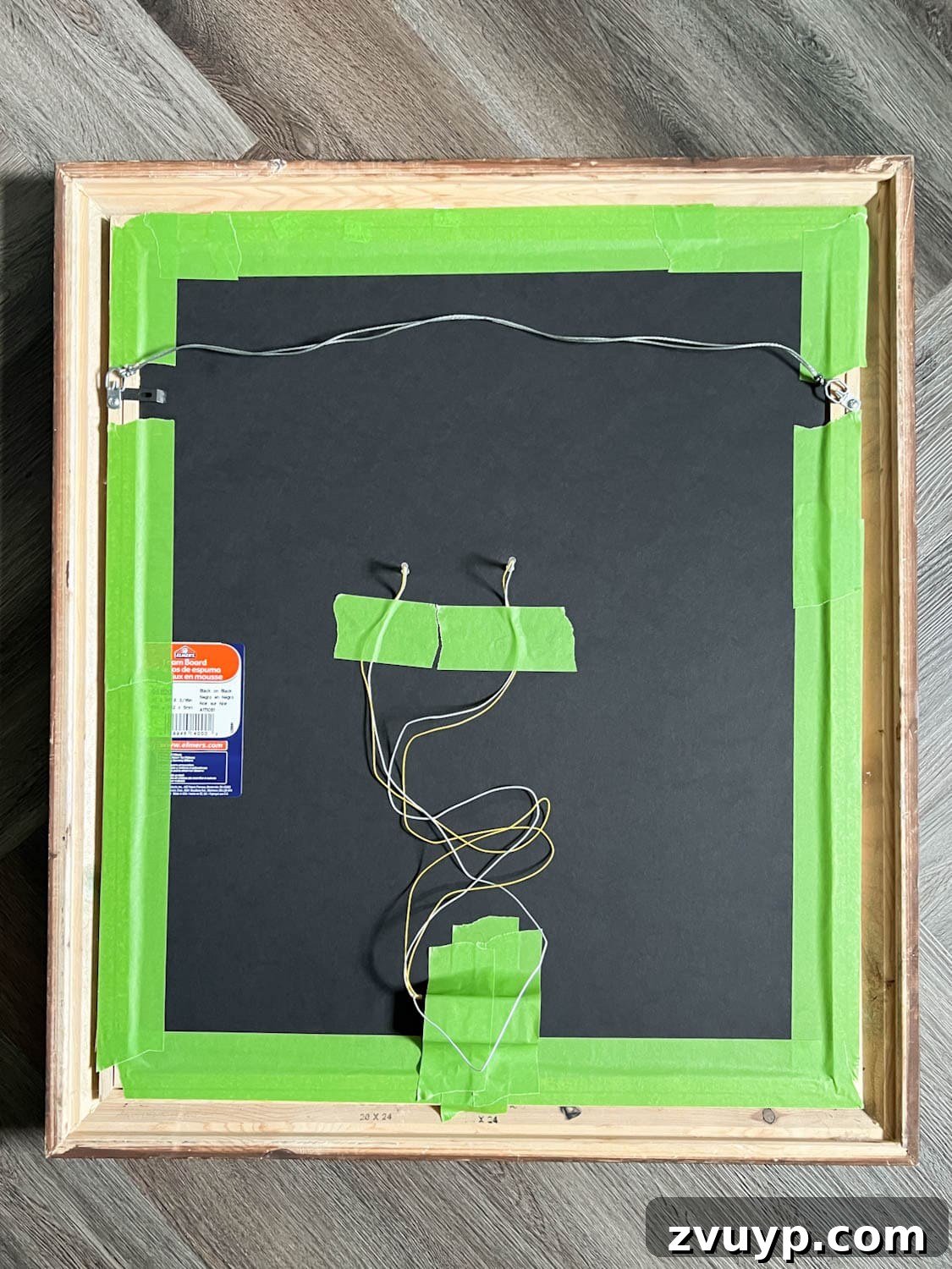 Red battery lights taped to the back of a Halloween art portrait, ready to glow.