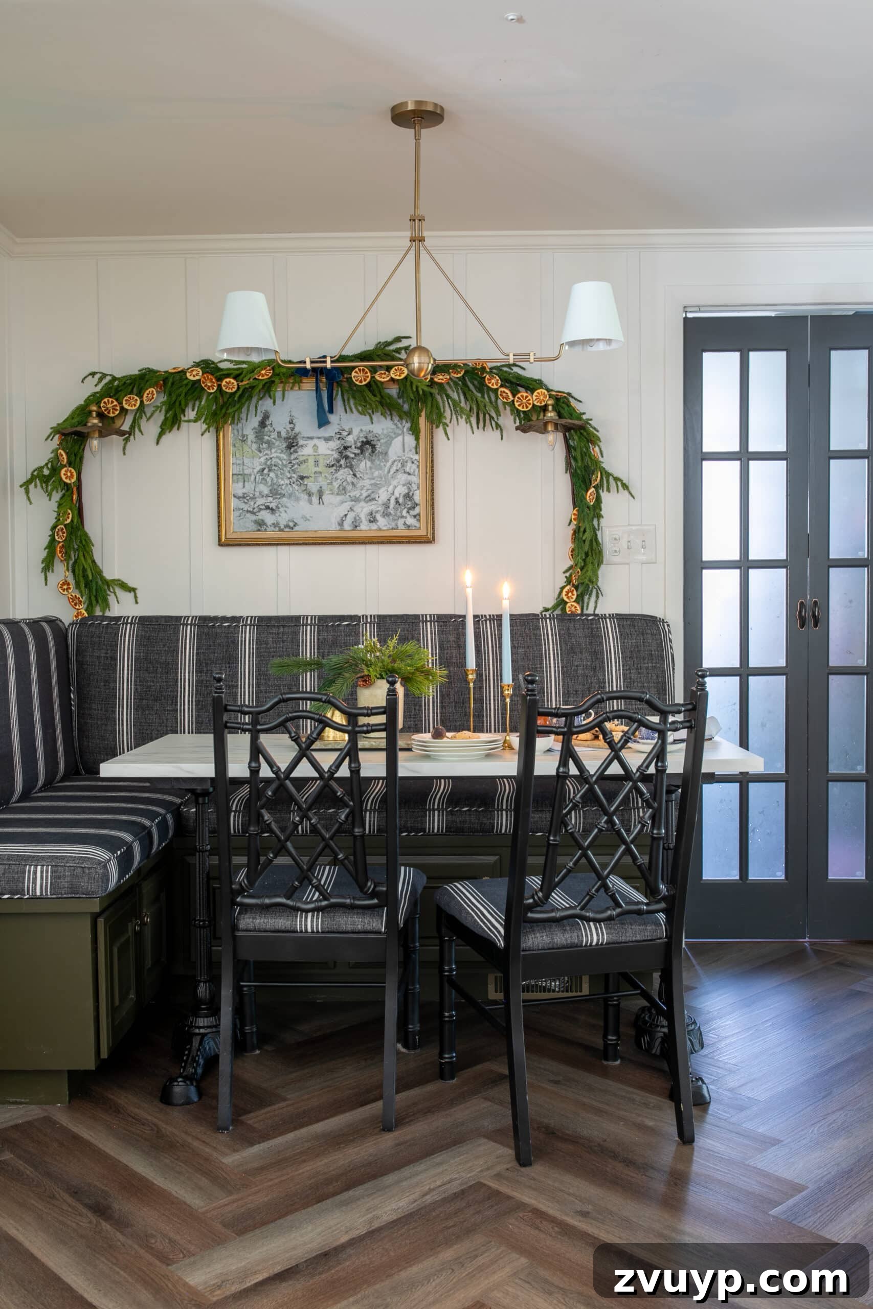 Free Printable Winter Art for Instant Home Decor 9 Charming breakfast nook elegantly decorated for Christmas, featuring lush garland and a serene snow art piece on the wall, creating a festive and inviting space for the holidays.