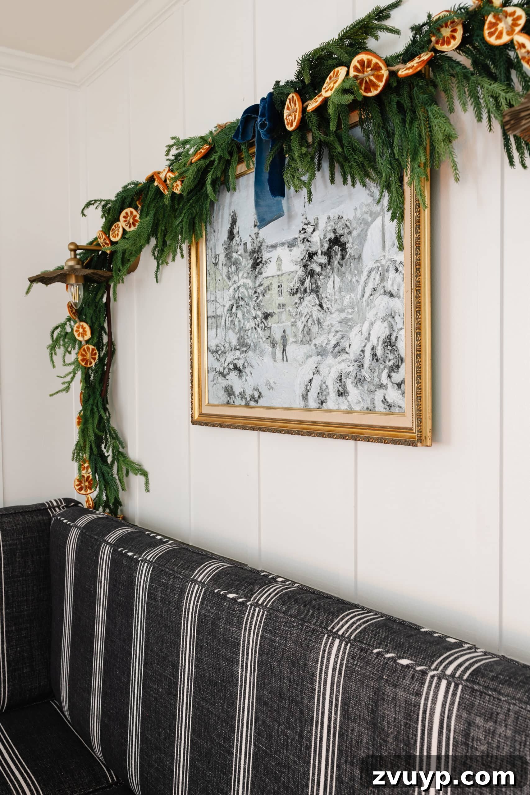 Free Printable Winter Art for Instant Home Decor 3 Elegant winter painting displayed in a gold thrifted frame, adorned with festive pine garland and natural orange slices, creating a cozy holiday atmosphere.