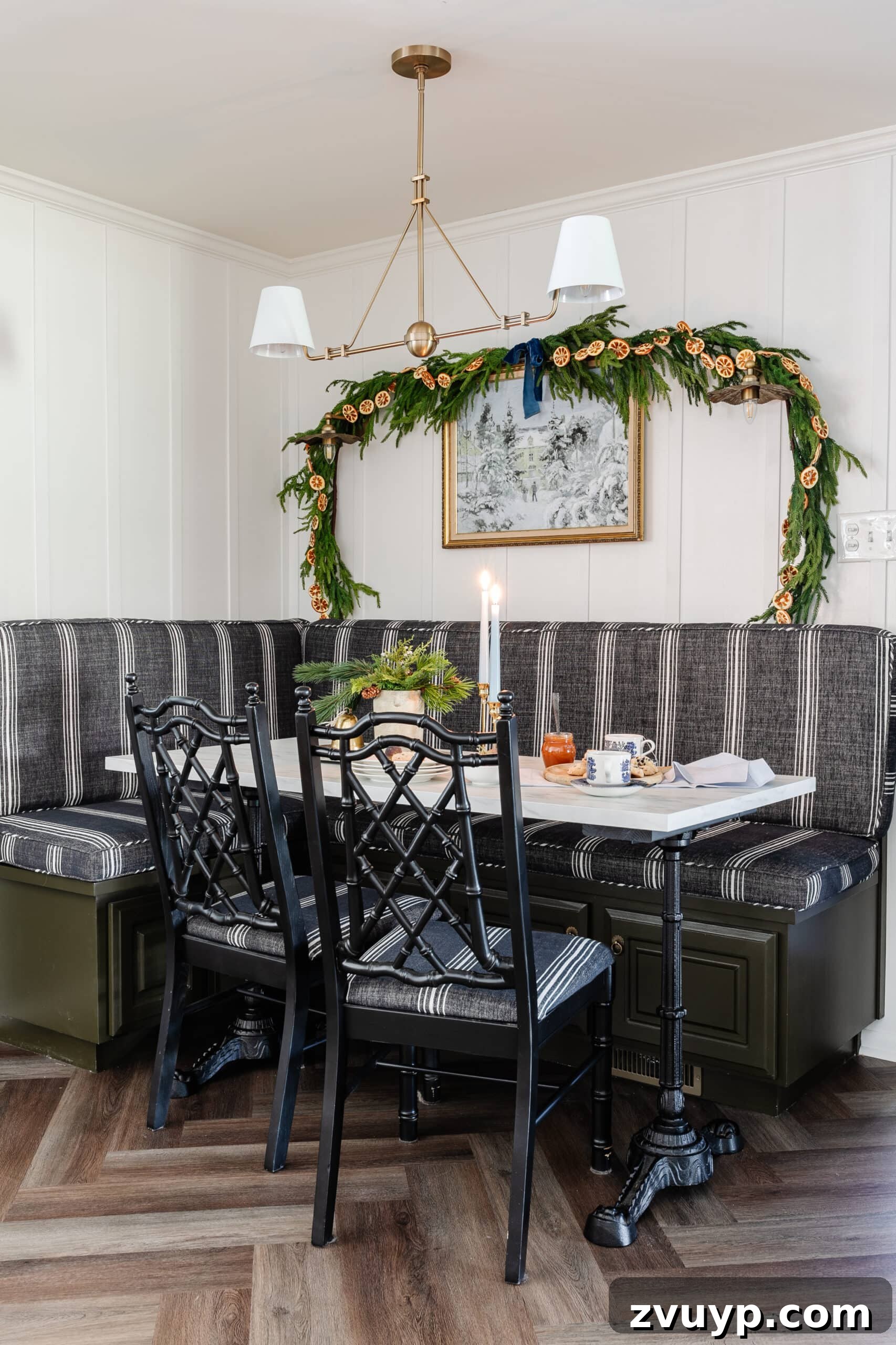 Free Printable Winter Art for Instant Home Decor 4 A festive Christmas kitchen table adorned with evergreen garland, complementing a beautiful winter scene art printable hanging on the wall, creating a warm and inviting atmosphere.