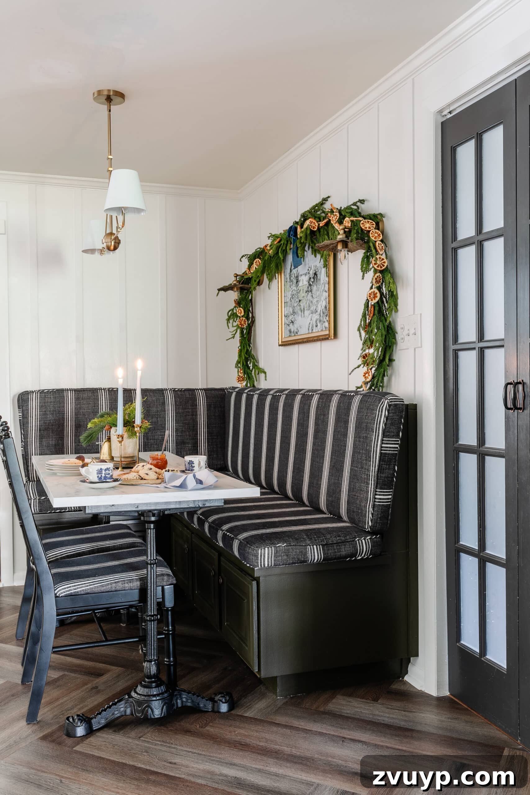 Free Printable Winter Art for Instant Home Decor 6 Cozy breakfast nook banquette and table adorned with charming Christmas decor, featuring a winter painting as the focal point, creating an inviting seasonal dining area.