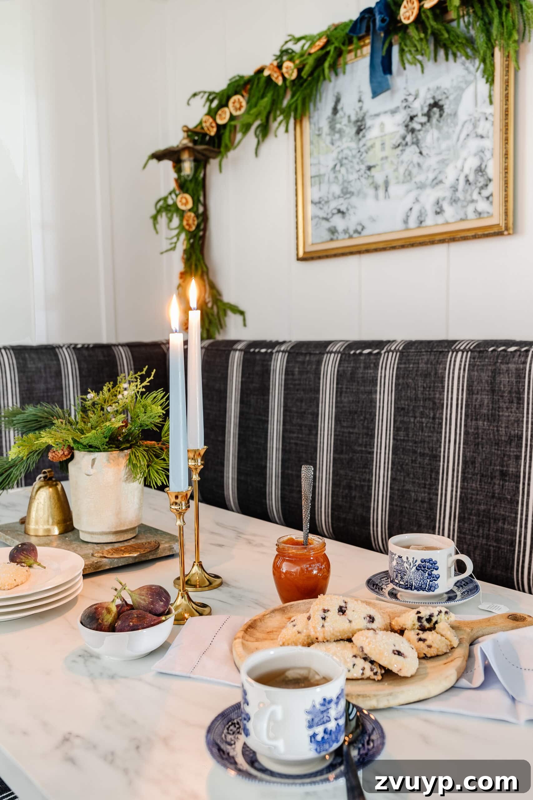 Free Printable Winter Art for Instant Home Decor 7 A festive Christmas kitchen table featuring a vase of fresh winter greenery, a beautiful winter painting on the wall, and elegant garland, creating a warm and inviting atmosphere for holiday gatherings.