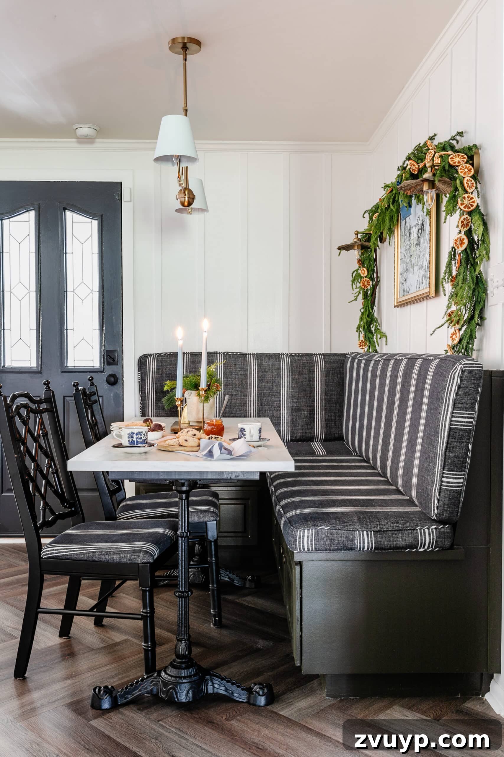Free Printable Winter Art for Instant Home Decor 8 Cozy breakfast nook featuring a banquette and kitchen table beautifully decorated for Christmas, adorned with a vase of winter stems and festive accents, creating a warm and inviting space.