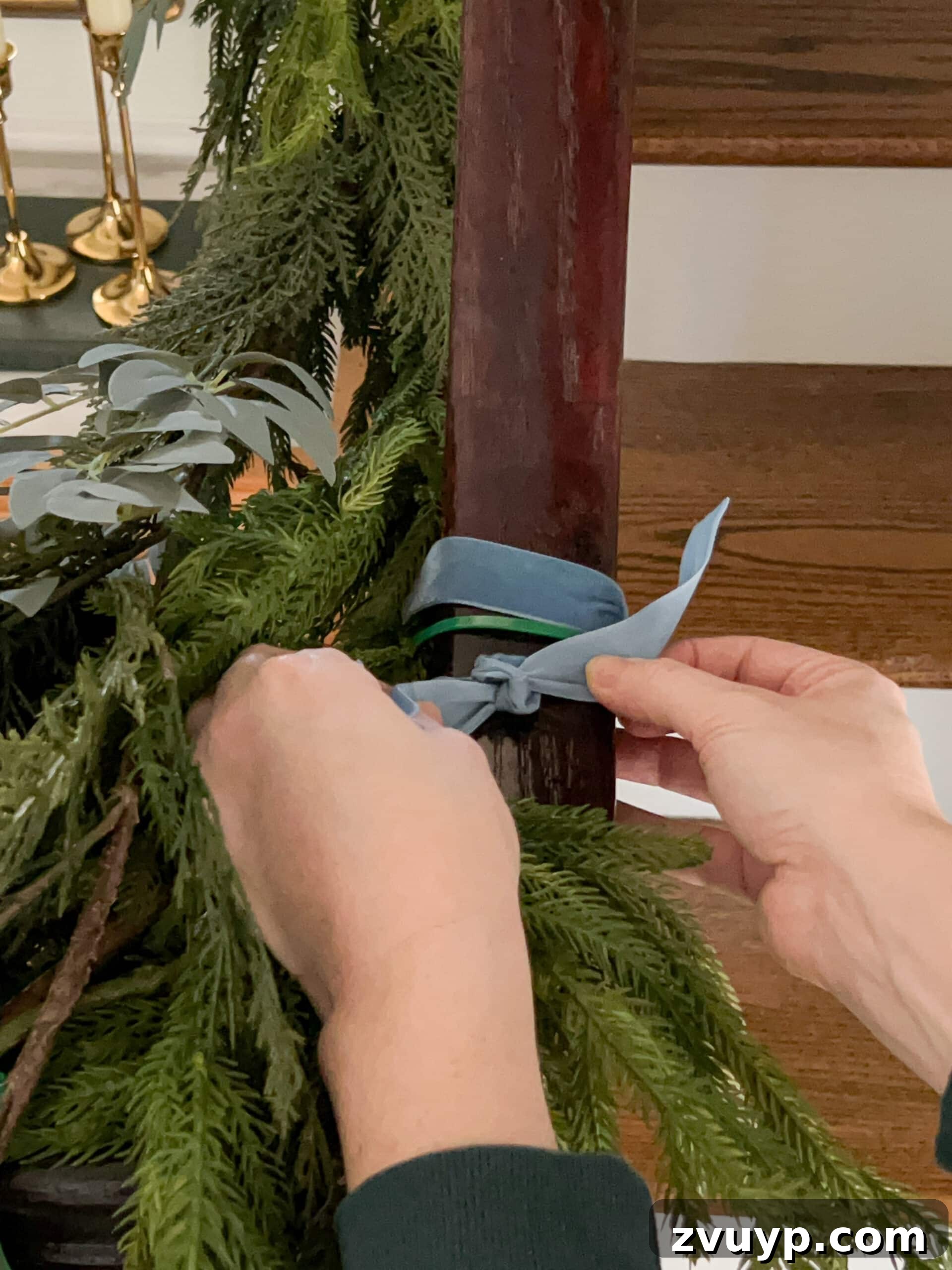 Deck the Halls Staircase and Entryway Christmas Garland Decor 11 adding ribbon to cover zip ties on staircase garland