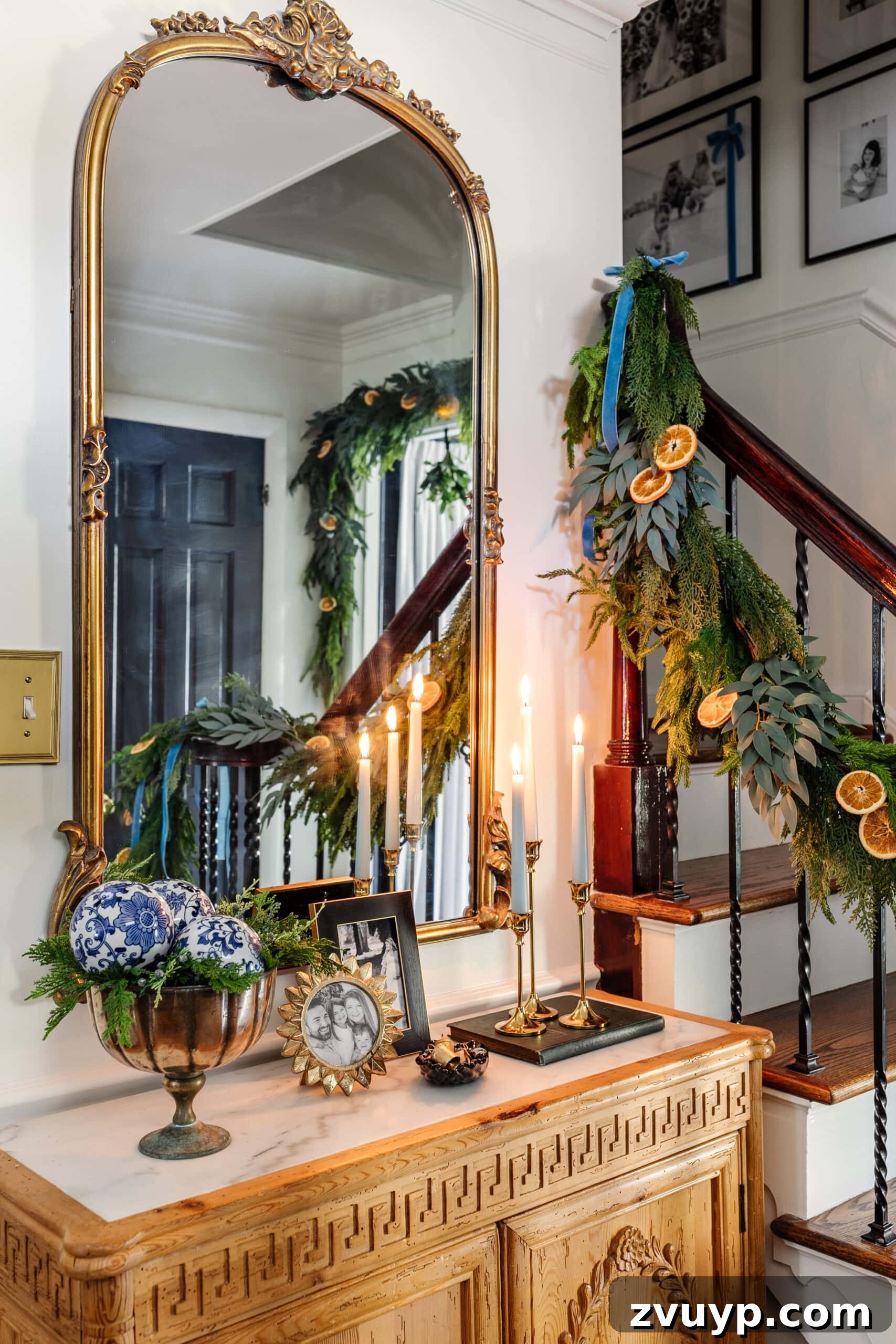 Deck the Halls Staircase and Entryway Christmas Garland Decor 19 entryway Christmas decor on a table with candles, mirror, picture frames, and bowl of greenery