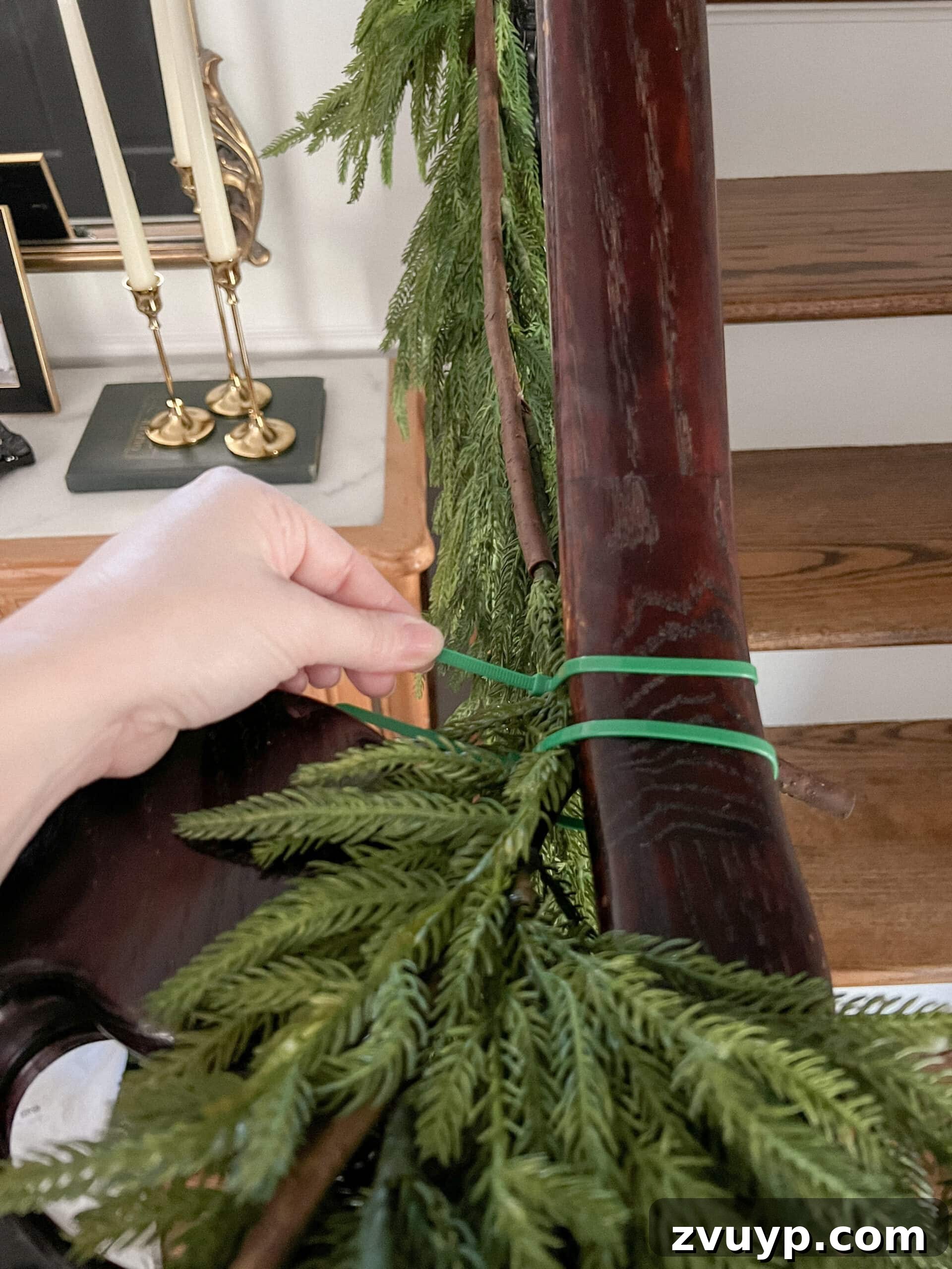Deck the Halls Staircase and Entryway Christmas Garland Decor 5 securing garland on stairs banister with zip ties