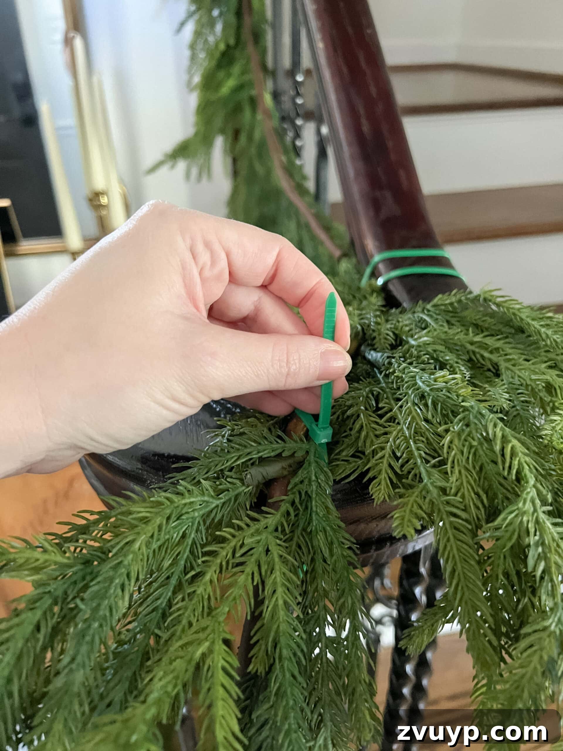 Deck the Halls Staircase and Entryway Christmas Garland Decor 6 securing garland on stairs banister with zip ties