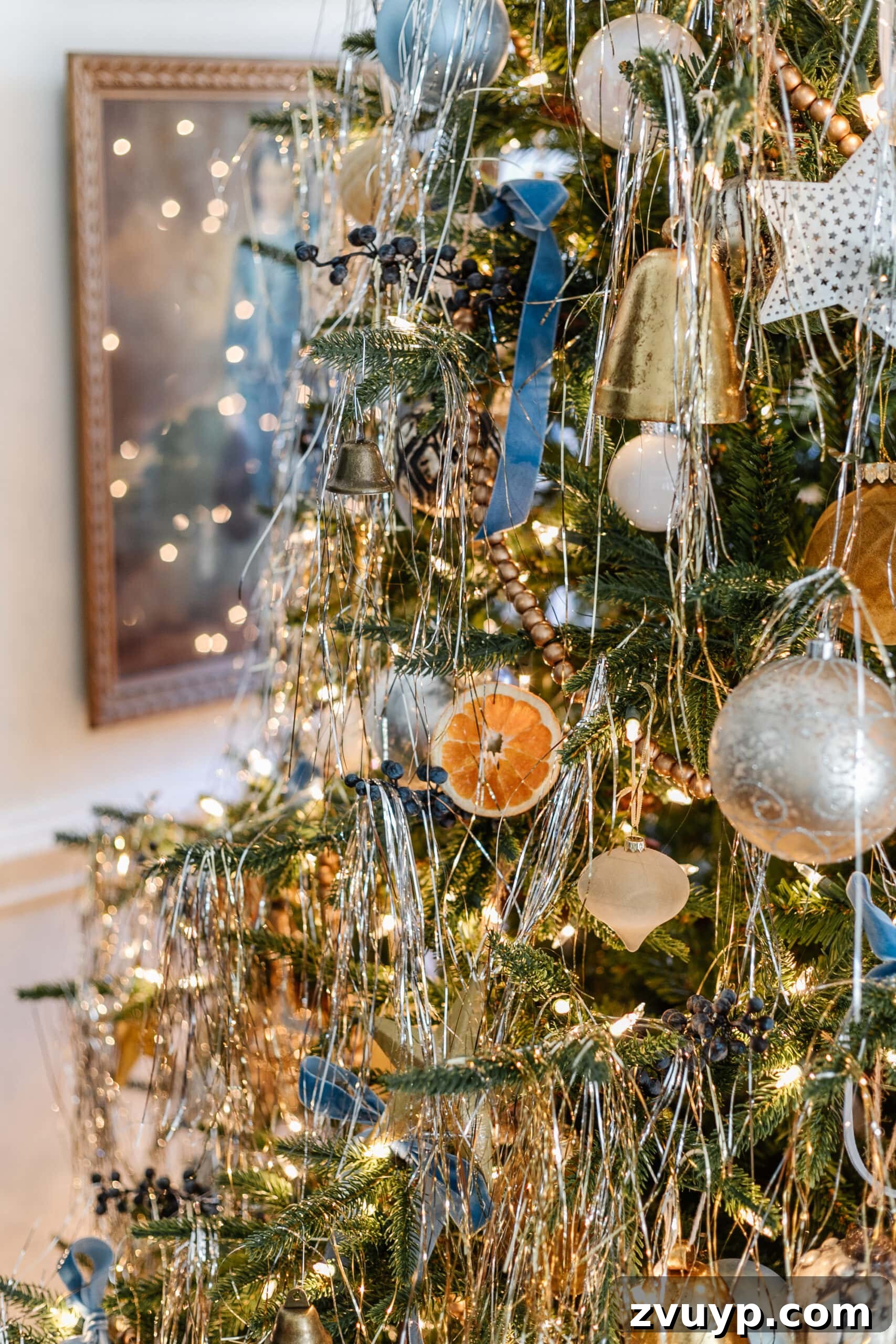 Festive Comfort: Living Room Decor for a Magical Christmas 13 A festive Christmas tree adorned with shimmering tinsel, classic ball ornaments, and unique dried orange slices, creating a harmonious blend of traditional and natural decor.