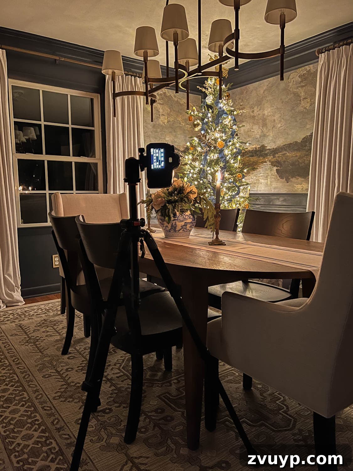 Karanlıkta Parıldayanlar: Noel Ağacı Işıkları Fotoğrafçılığı ve Mum Işığı Gezintisi 7 A cozy holiday scene with a camera on a tripod capturing a Christmas tree, emphasizing the importance of stability for night photography.